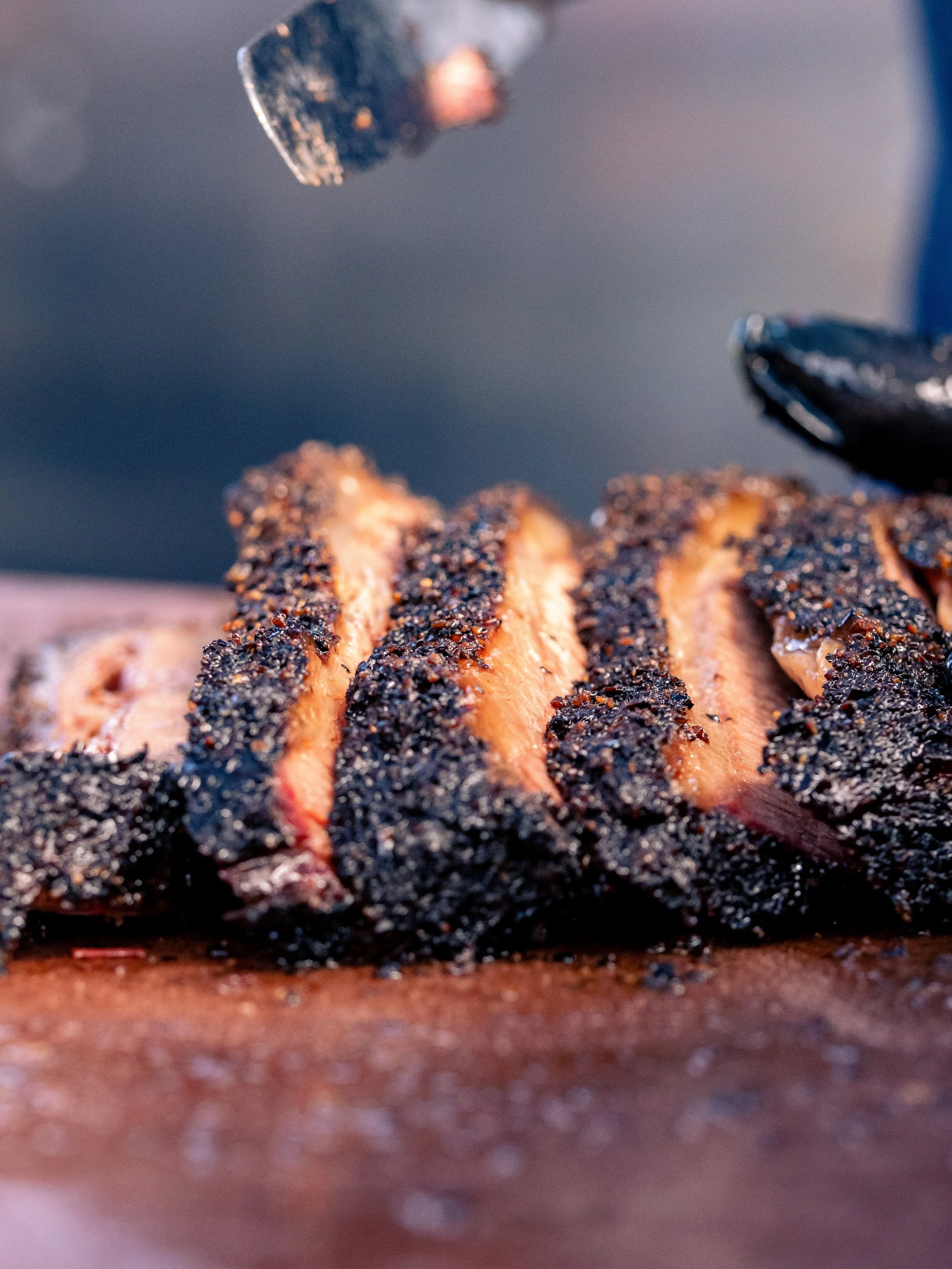 Close-up of grilled salmon with a black pepper crust cooking on a grill.