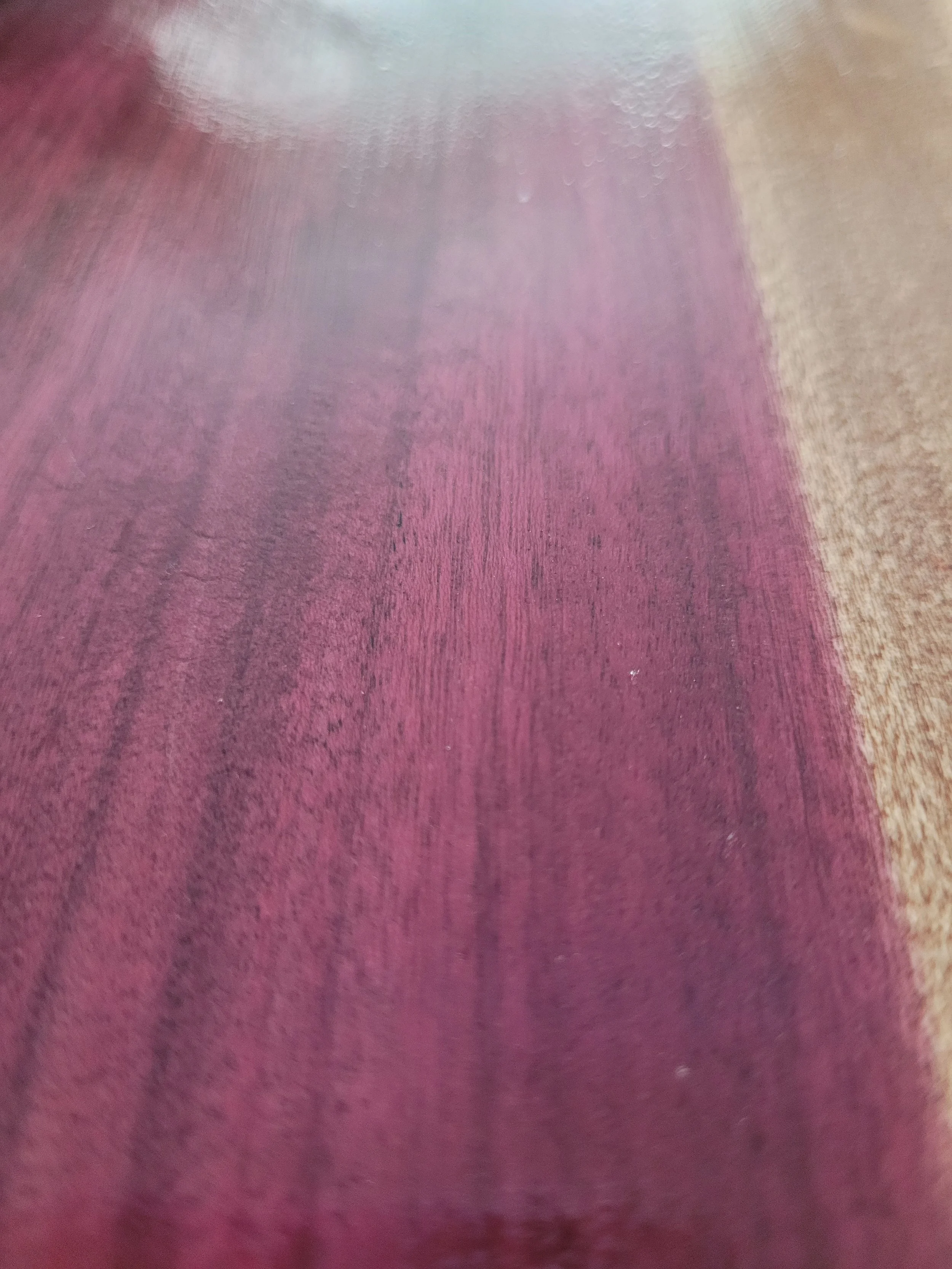 Close-up of a glossy wooden surface with a gradient of deep purple and pink hues.