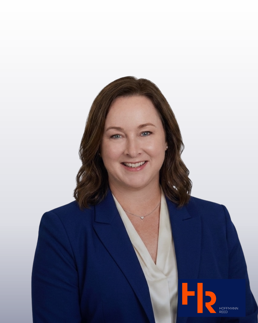 Professional headshot of a woman with shoulder-length brown hair, wearing a navy blue blazer and white blouse, smiling, with a background displaying a logo for Hoffmann Reed.