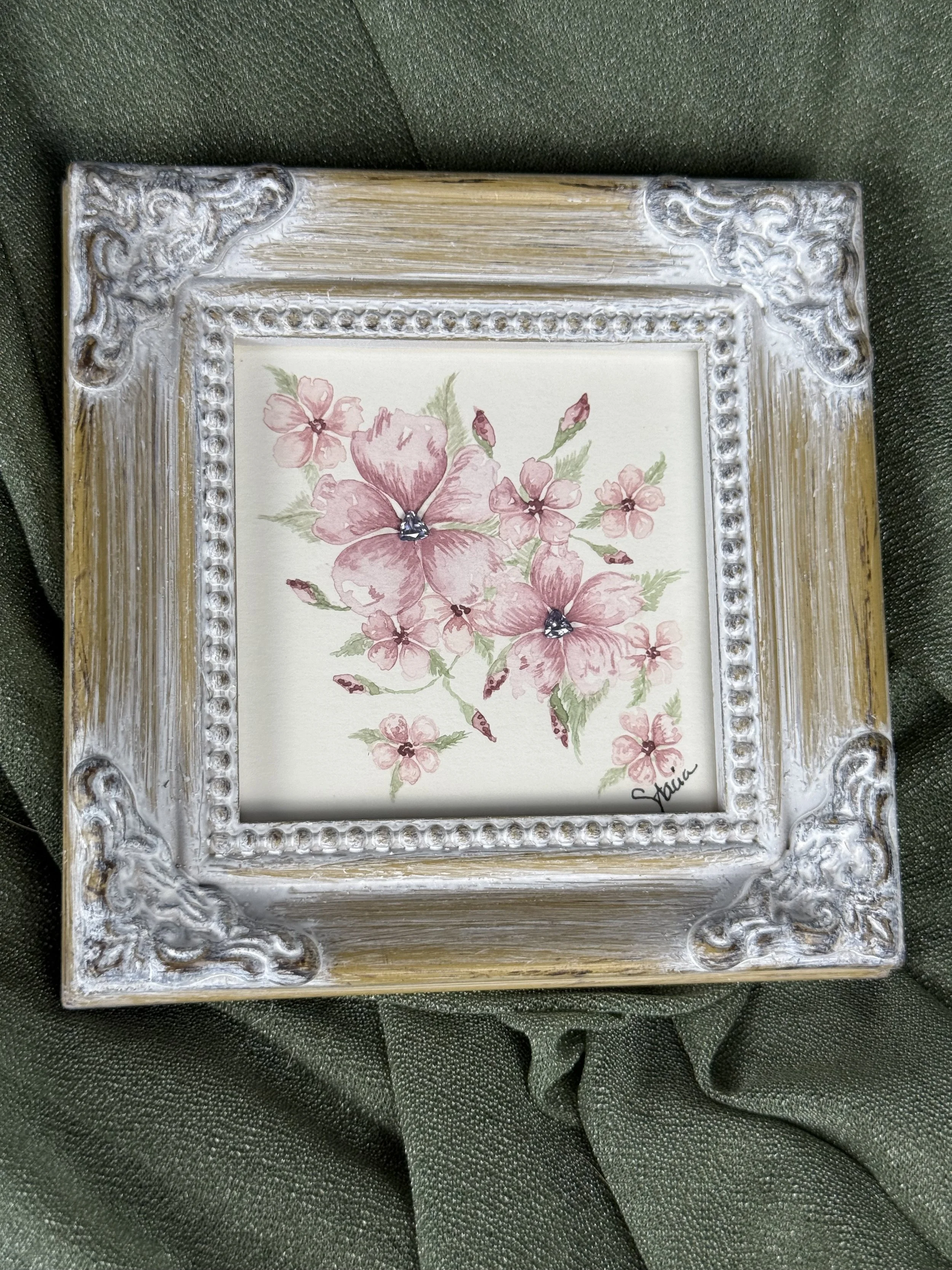 Blushing Bouquet watercolor painting of pink blossoms with two lab-grown alexandrite gemstone centers in an ornate frame by Stacia Shane