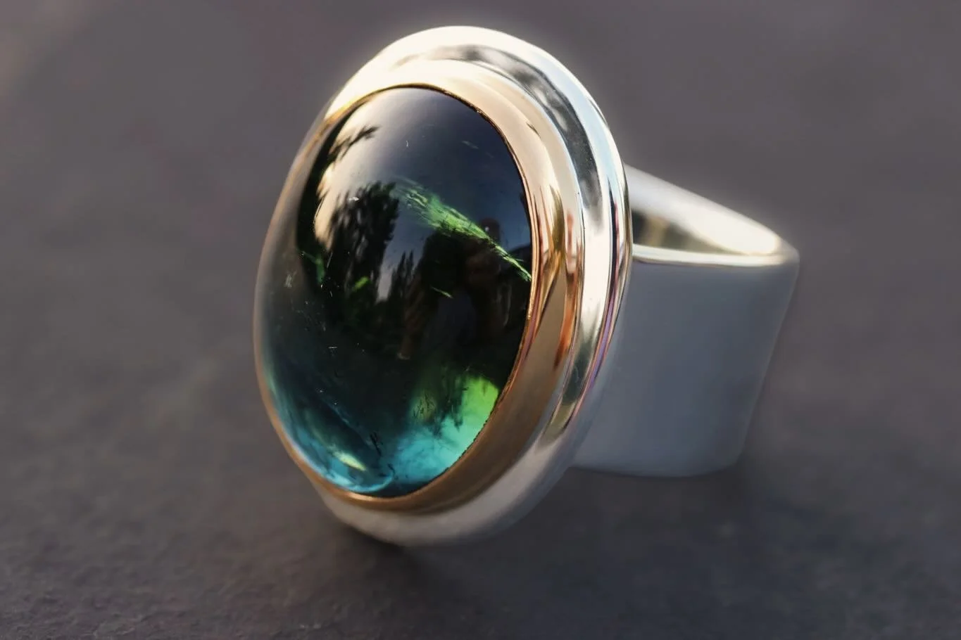 Bi-color tourmaline set in 22k gold and silver. Green to blue, the stone never looks the same twice. Real beauty is in the character, the subtle, the truly unique. Wide band forged by hand, relieved to fit the human hand. Refined simplicity, nothing 