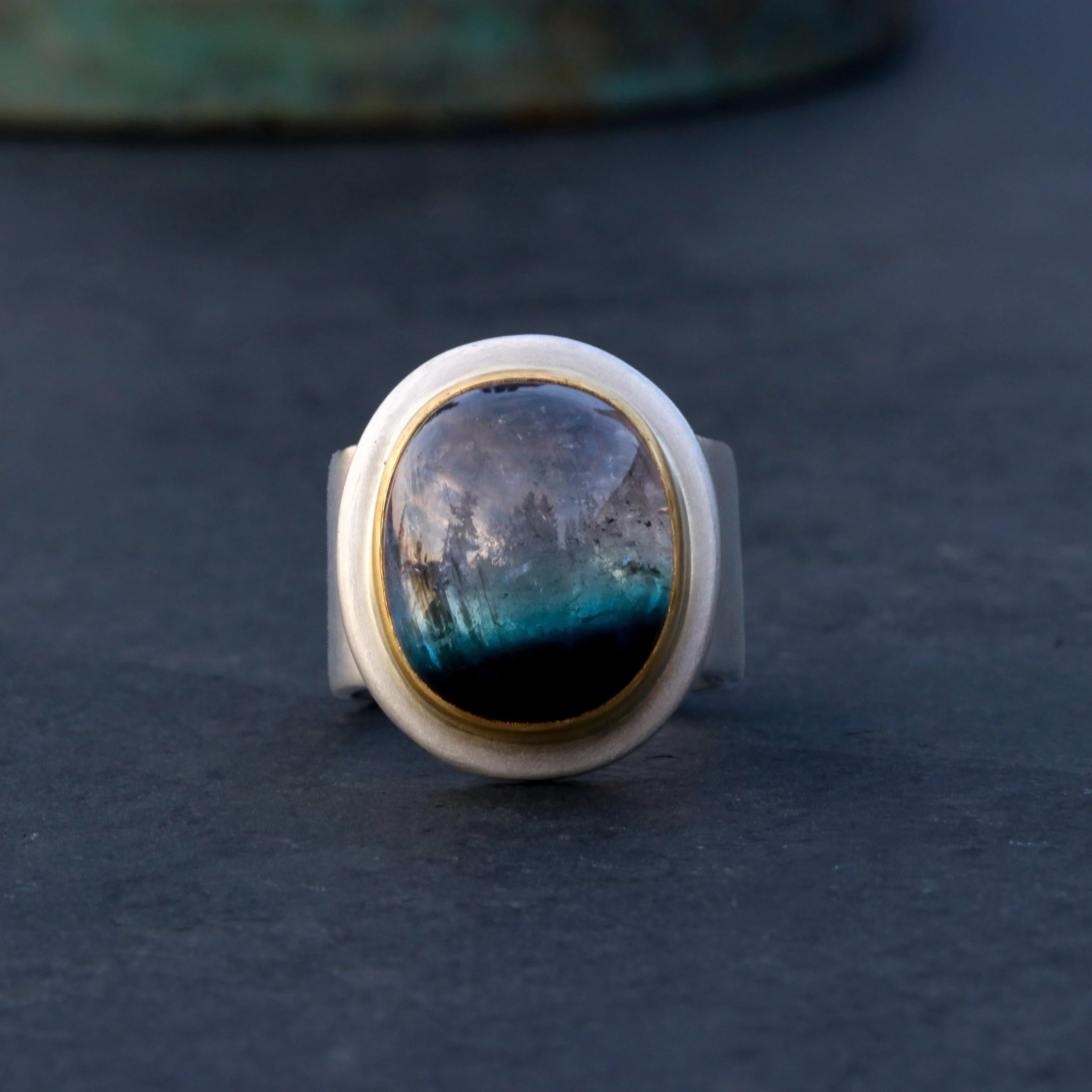 The dreamer invites you to dive in (or step in if you are not a diver).
 A whole universe within where one could float on a brilliant blue horizon atop the depths and peer up at a violet sky. 
&bull;
MULTICOLORED TOURMALINE/ 22K/SILVER WIDE BAND/ SAT