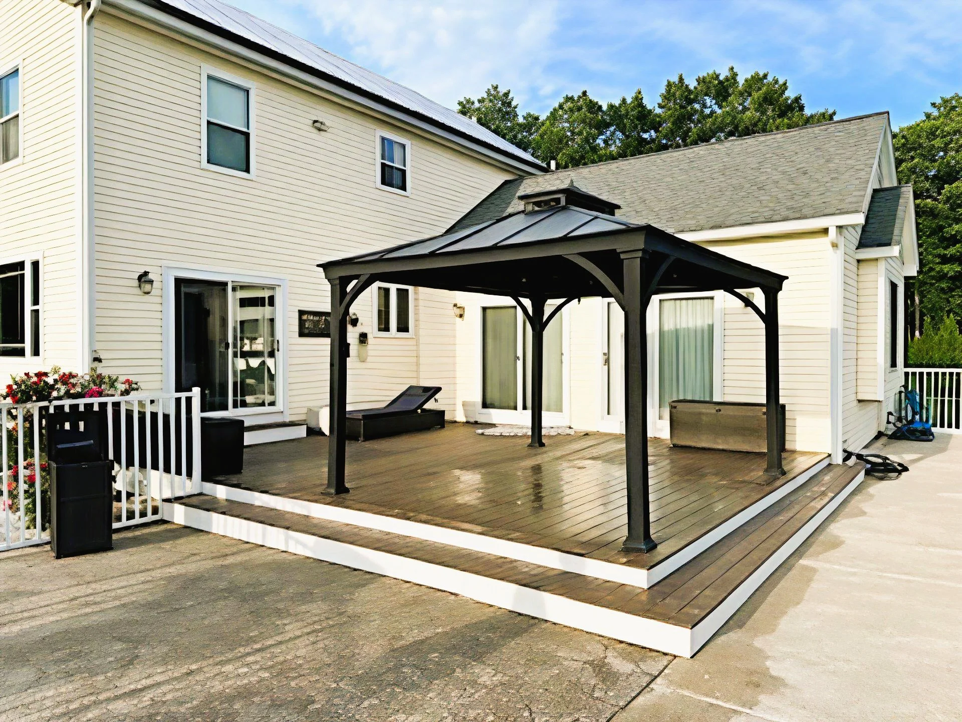 A house with a wooden deck, a gazebo, and sliding glass doors, 