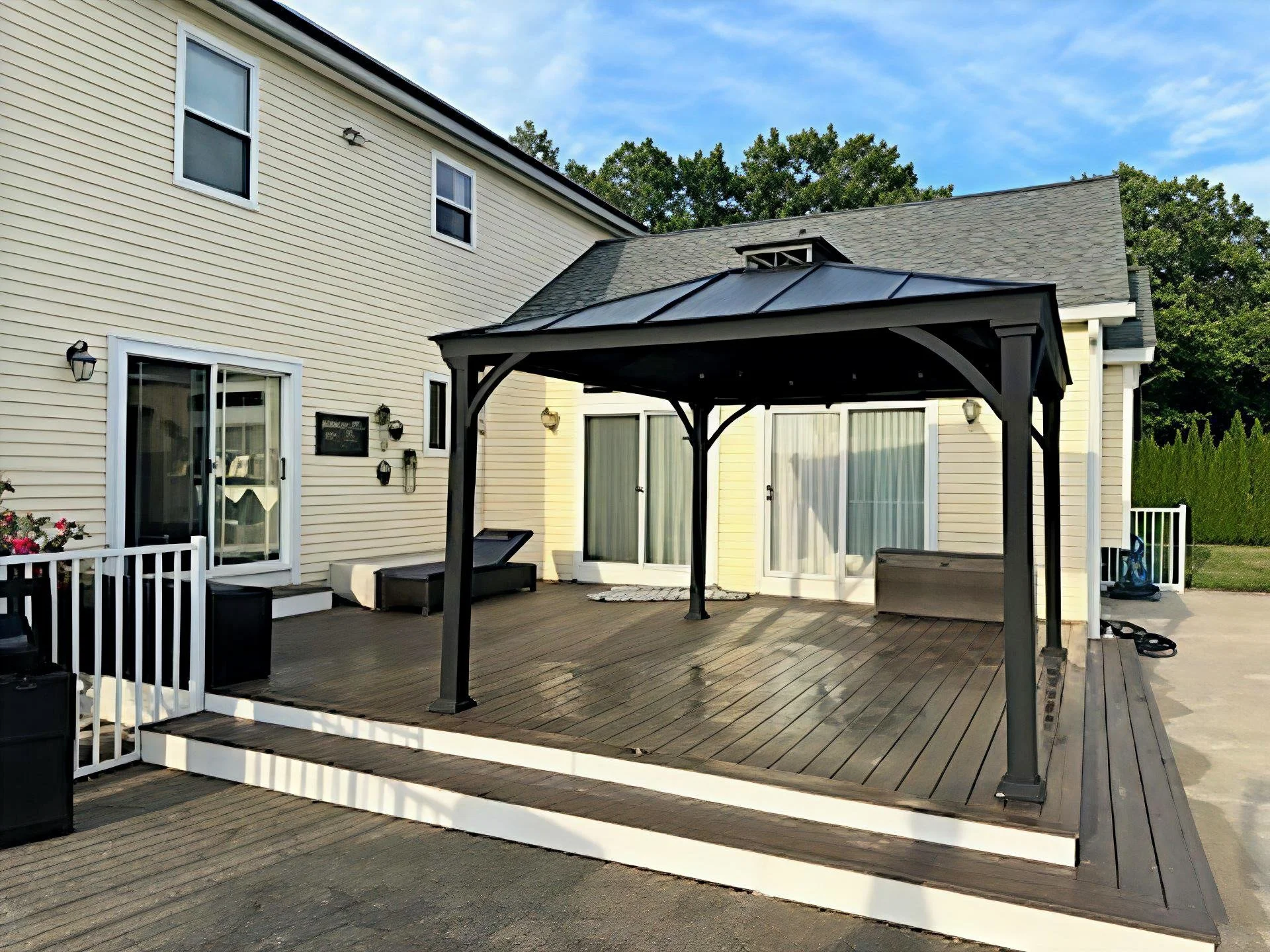Backyard deck with a black gazebo, outdoor furniture, and sliding glass doors leading to the house, 