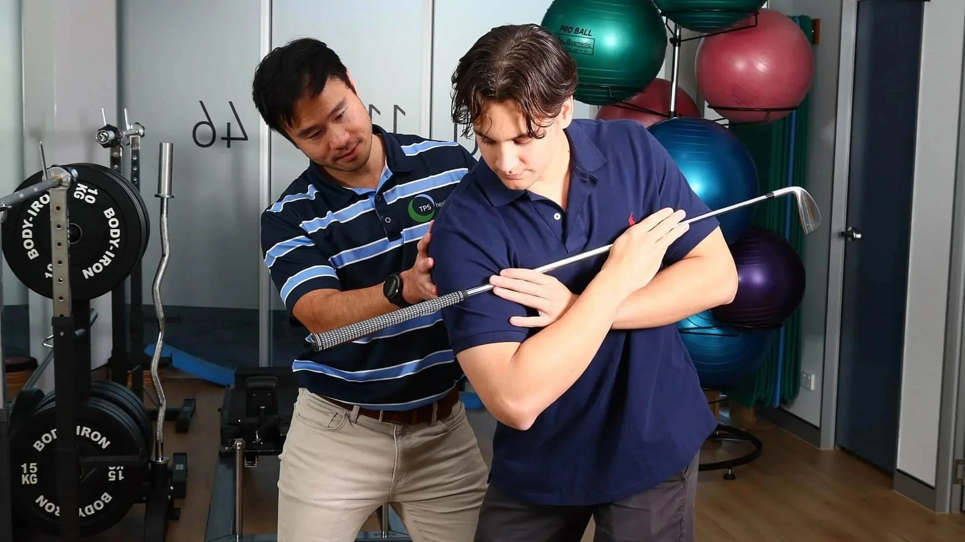 A physiotherapist conducts a golf physiotherapy assessment on a male patient in a physiotheraphy gym.