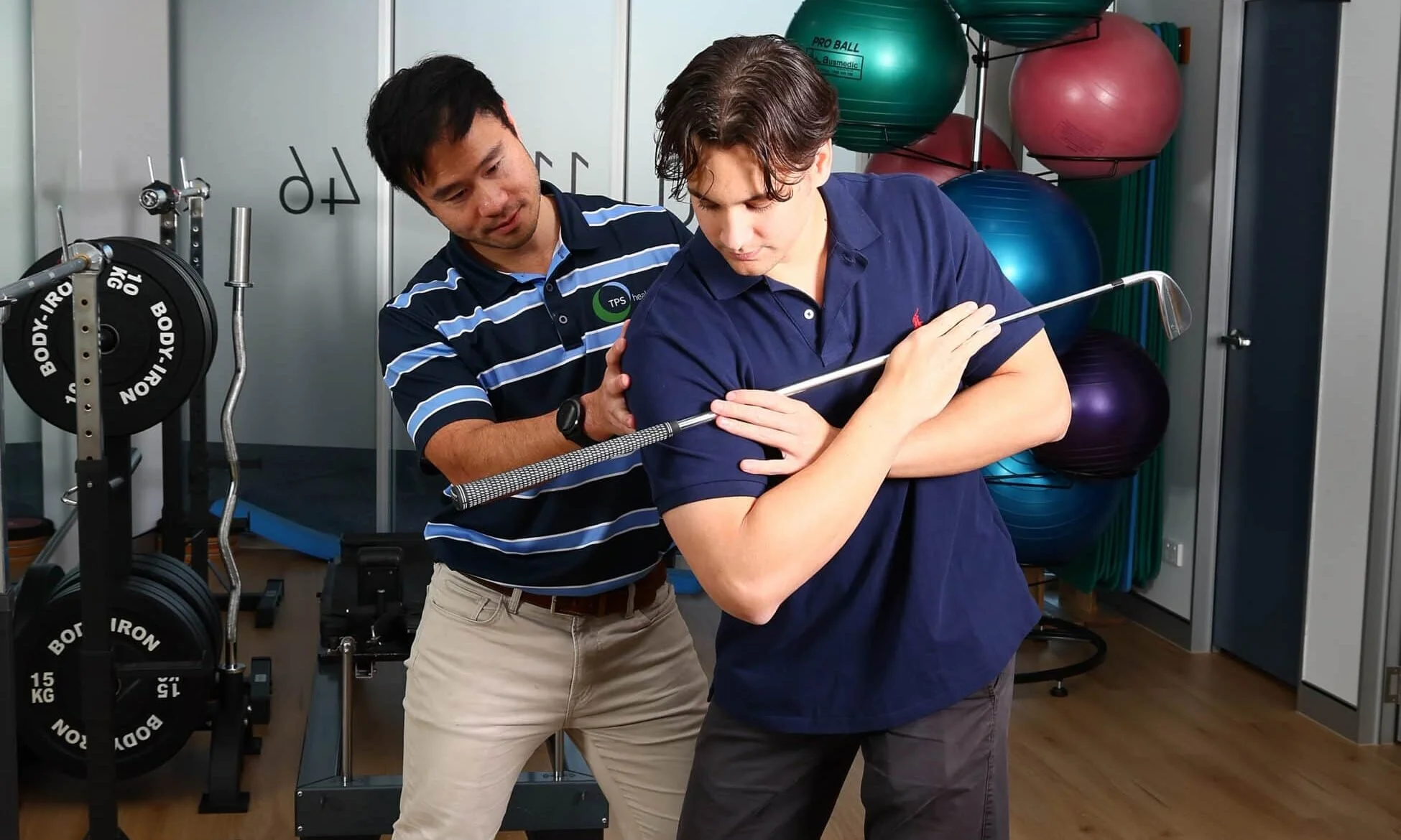 A physiotherapist conducts a golf physiotherapy assessment on a male patient in a physiotheraphy gym.