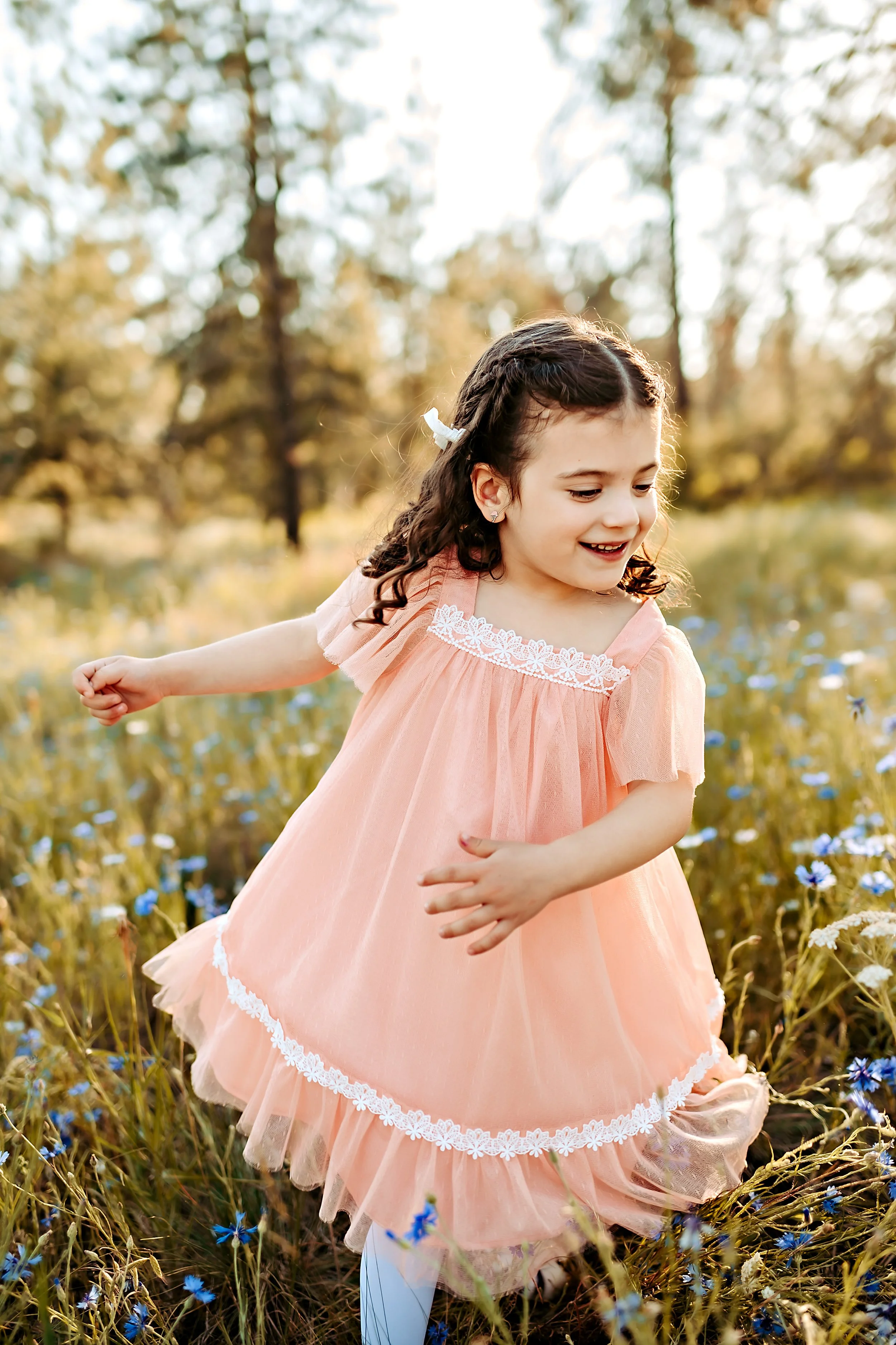 Ellie Grace at 5-years old, twirling in a pink dress in a field of wildflowers.