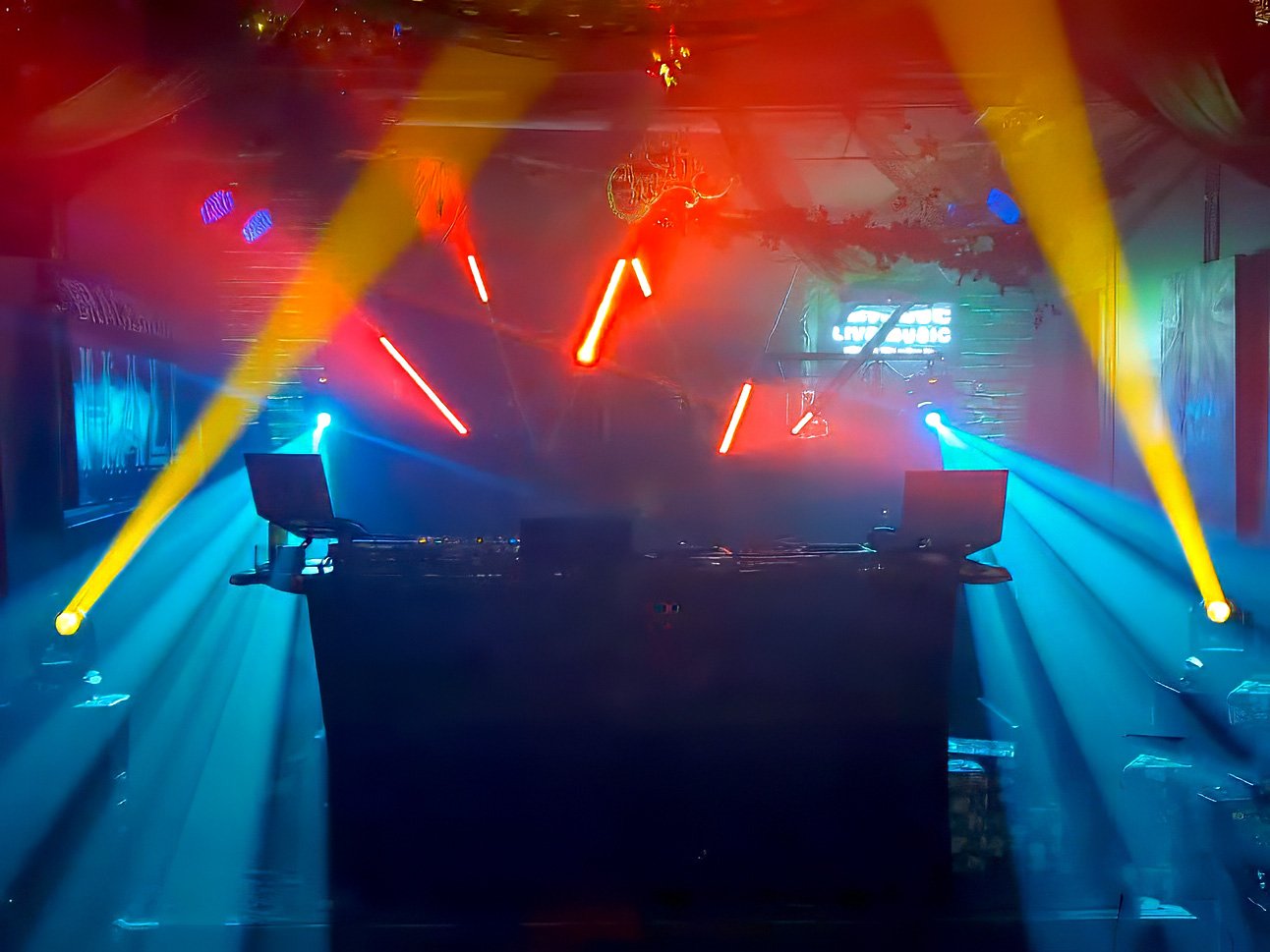 Colorful DJ stage with laser lights and smoke effect in a nightclub.