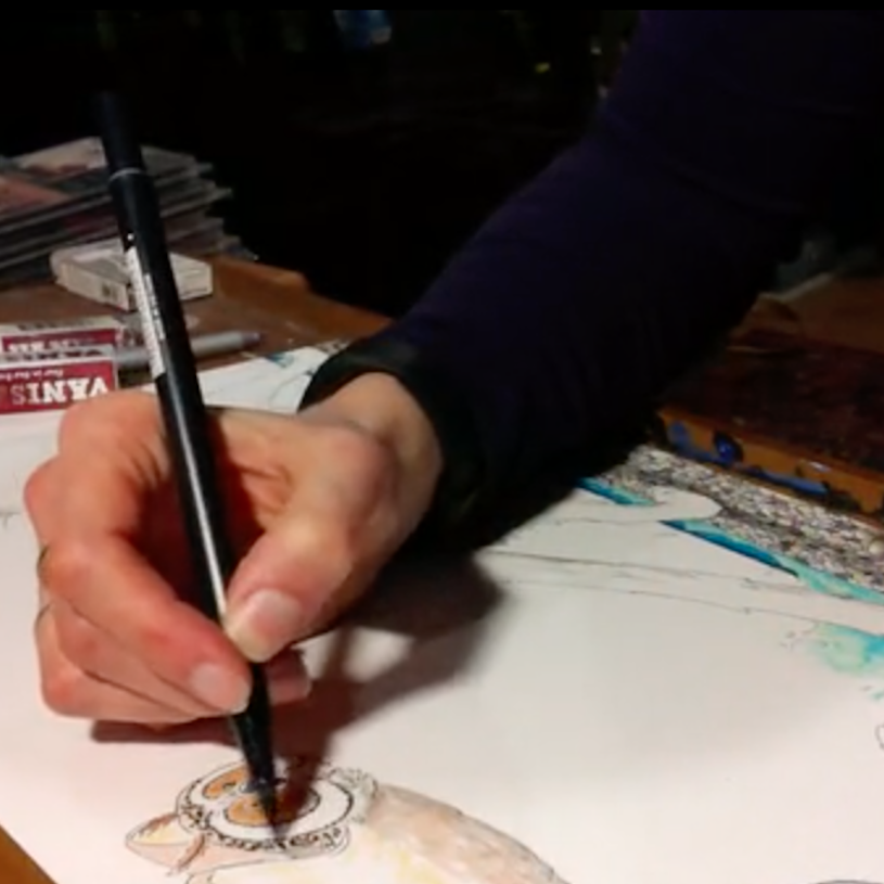 A person is drawing or painting a picture of a lion on paper with colored pencils or markers, with art supplies and sketches visible on the table.