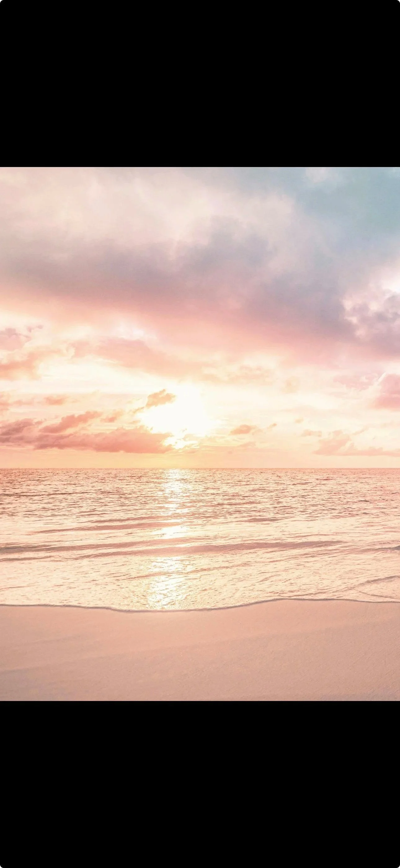 Sunset over the ocean with pink, orange, and purple clouds and calm water