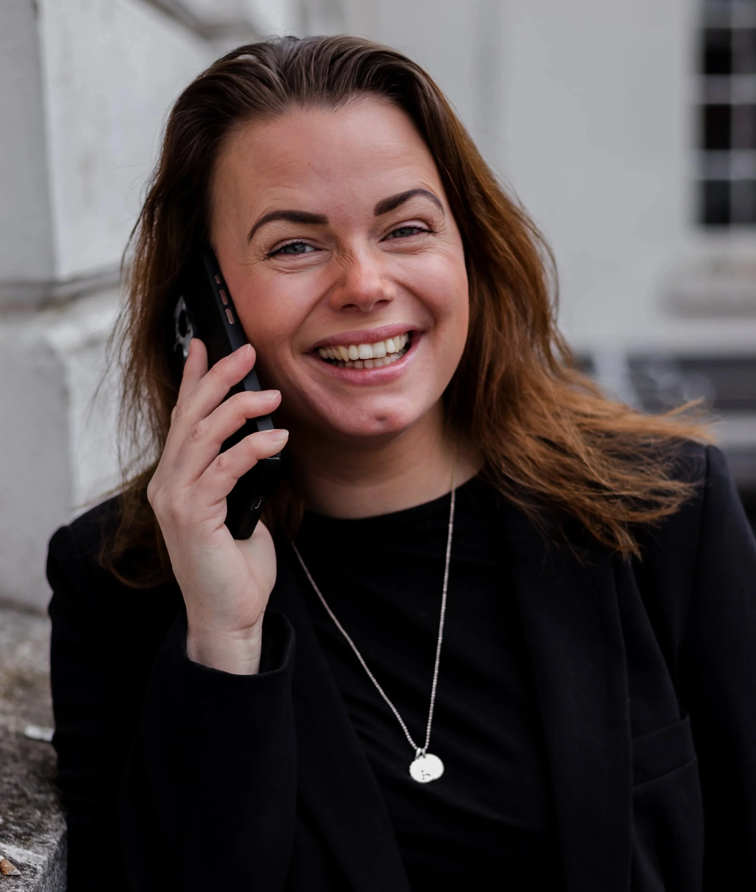 Kvinne snakker i telefon utendørs – dialog med kunder og oppfølging av prosjekter.