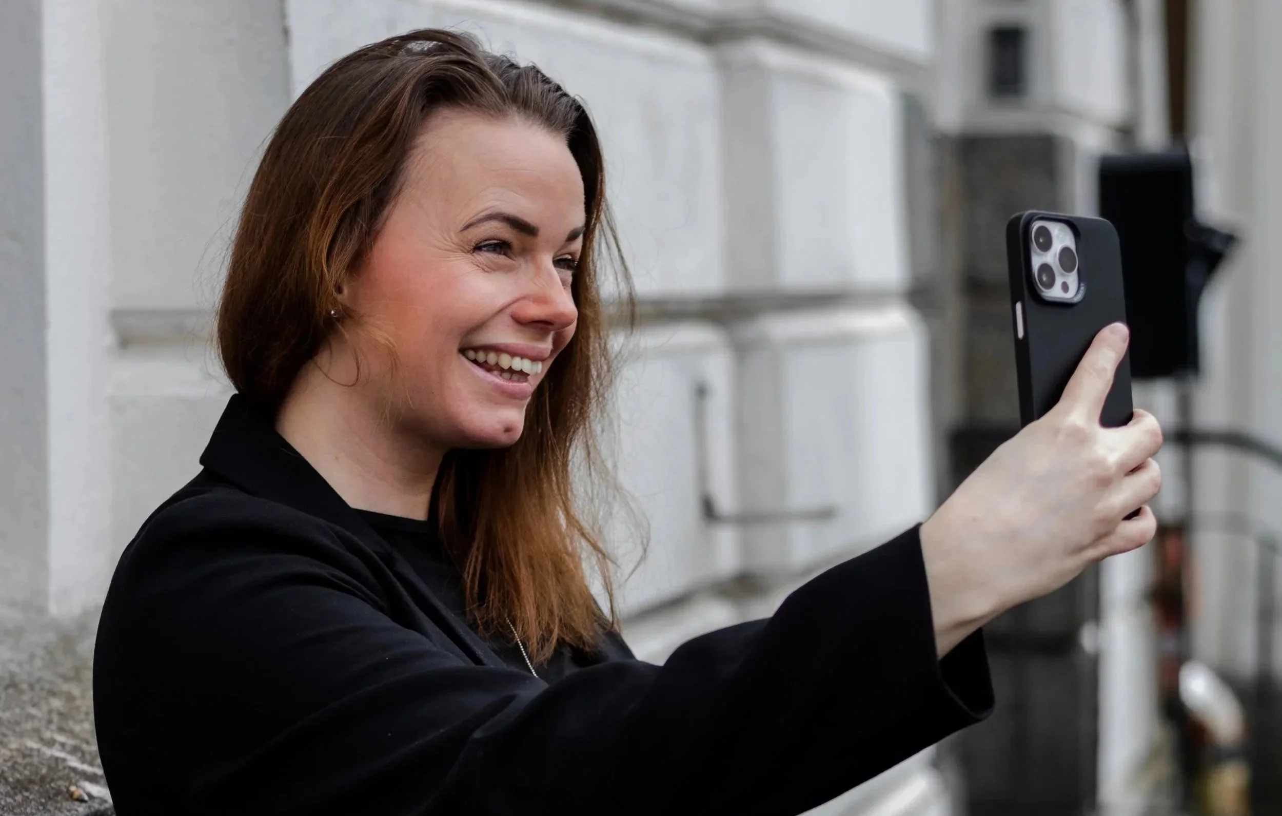 Kvinne sitter i sofa med laptop og gir tommel opp – fornøyd med nettside og digitalt oppsett.