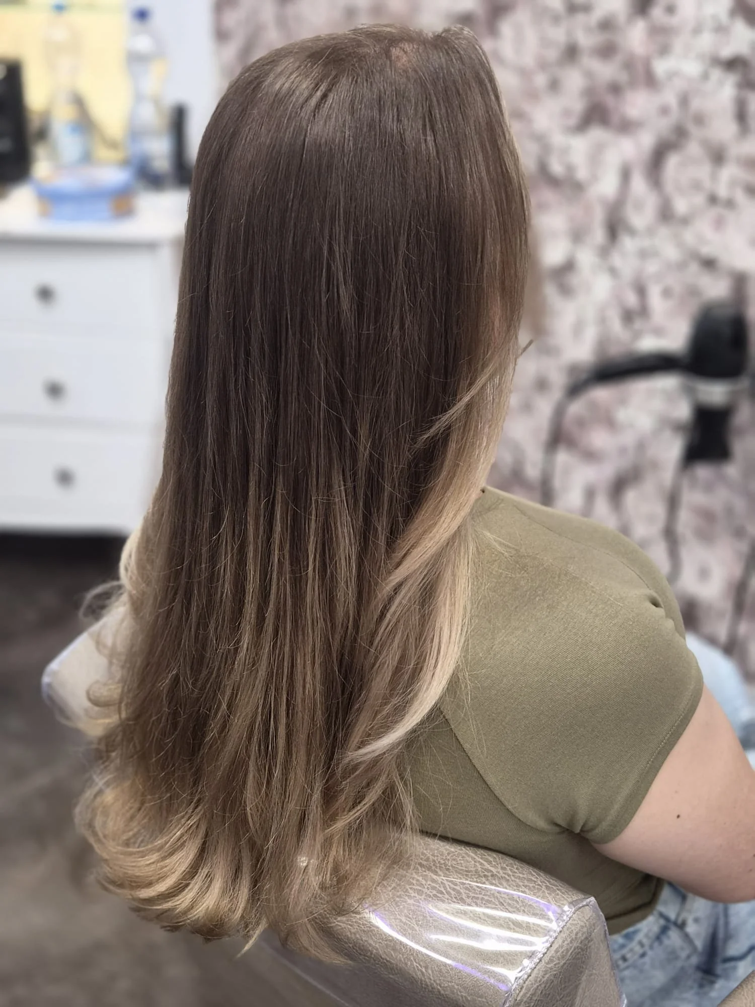 Aufnahme eines Frisörsitzes mit langen, gestylten Haaren, die in verschiedenen Hellbraun- und Blondtönen gefärbt sind.