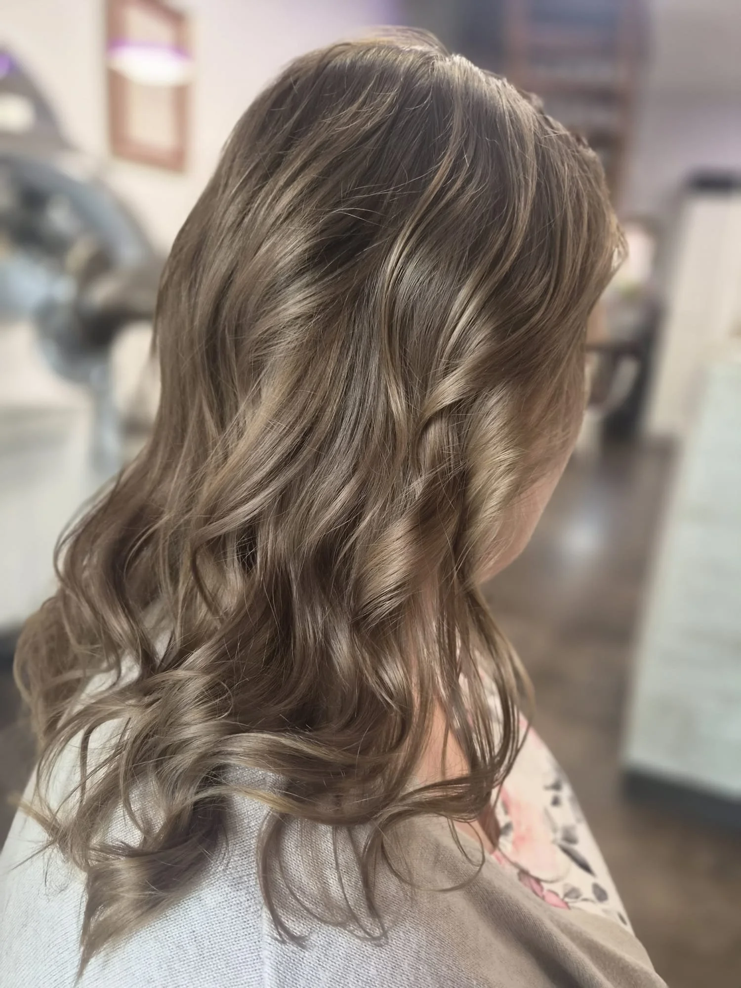 Nahaufnahme schulterlanges, gewelltes, schokoladenbraunes Haar in einem Friseursalon.