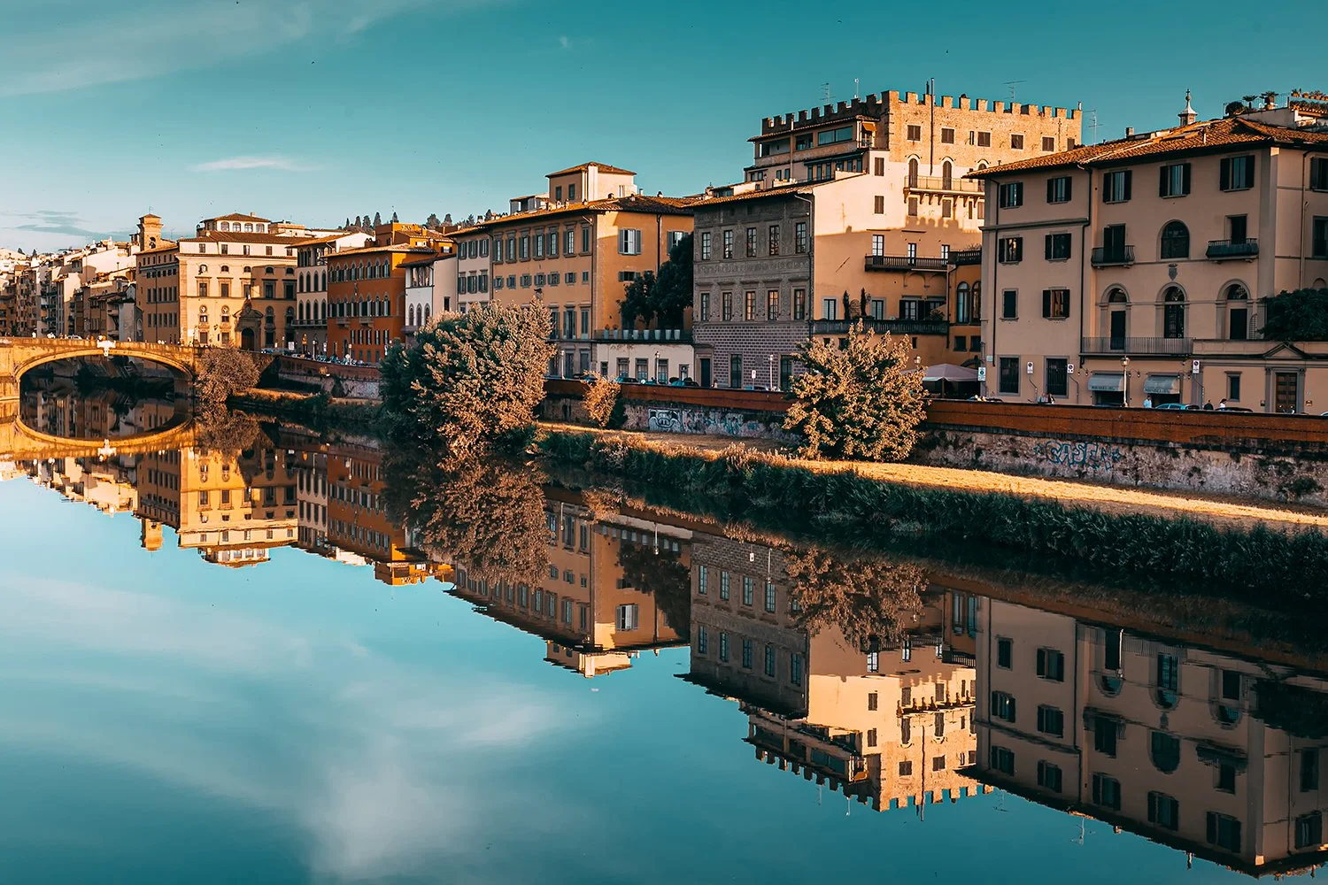 Historic Florence buildings reflected in calm river water.
