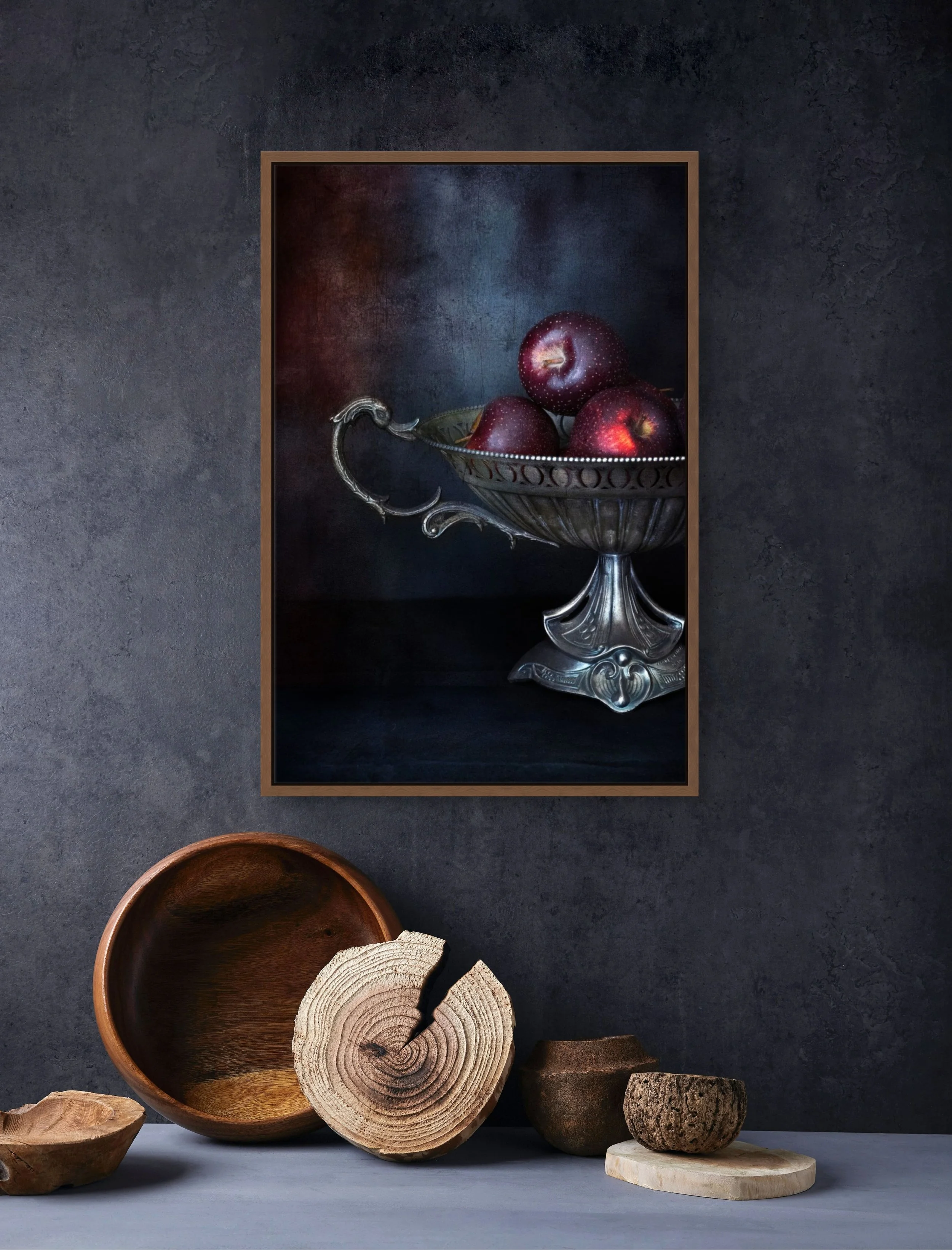 Red apples in antique silver bowl in moody still life photography.