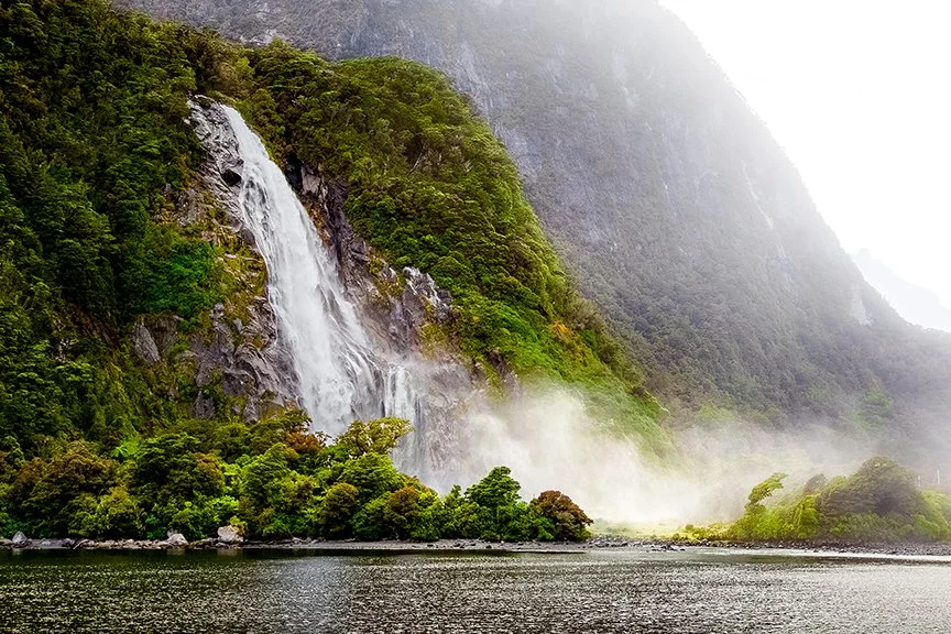 Lady Bowen Falls waterfall flowing down cliffs in Milford Sound New Zealand.