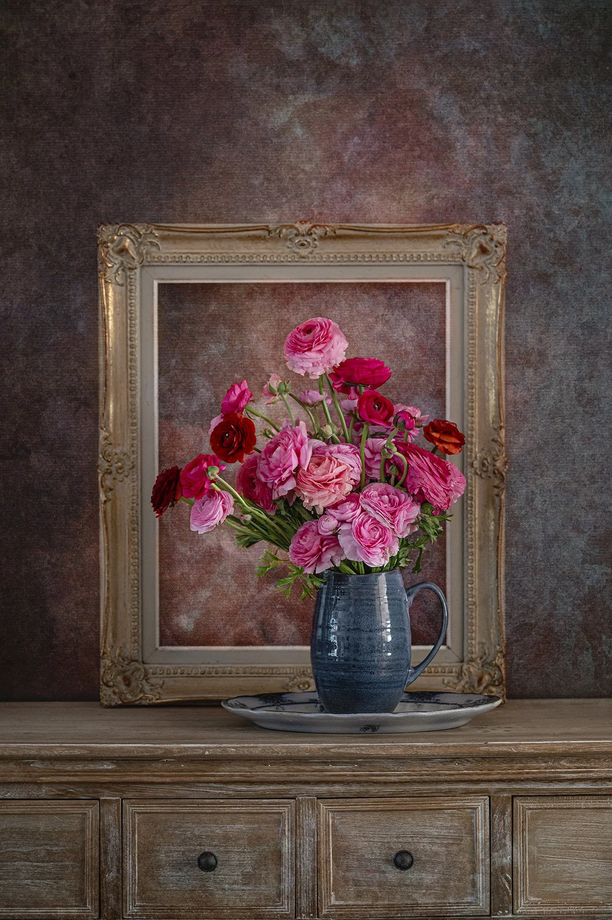 Pink and red ranunculus flowers in ceramic jug with vintage frame still life photography.