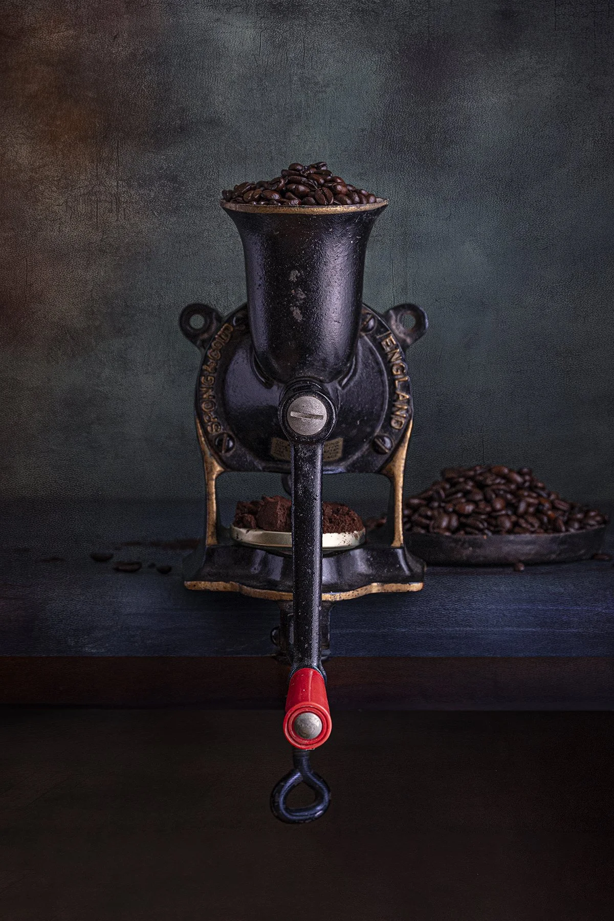 Vintage hand crank coffee grinder filled with coffee beans in still life photography.