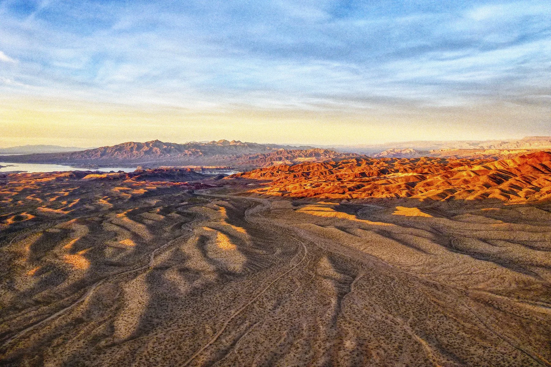Golden sunset light across desert ridges and distant mountains landscape.