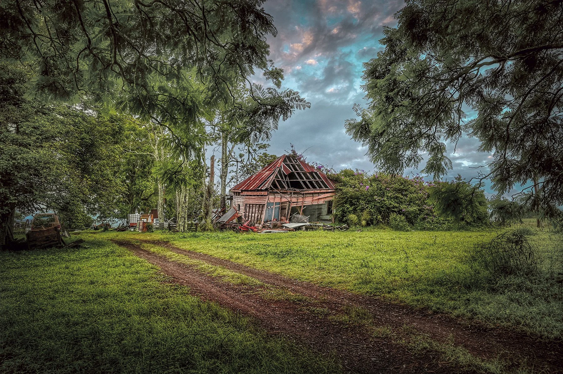 Old abandoned farmhouse surrounded by trees and countryside landscape.