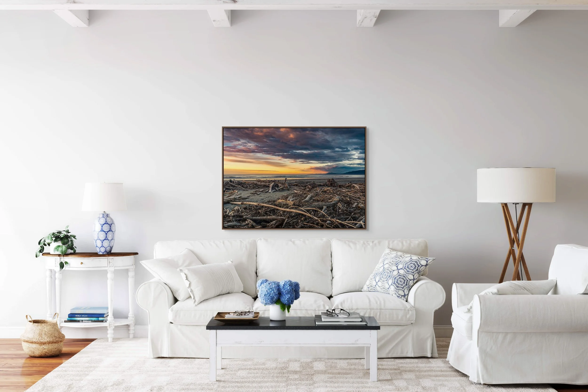 Driftwood scattered across a beach at sunset with mountains on the horizon.