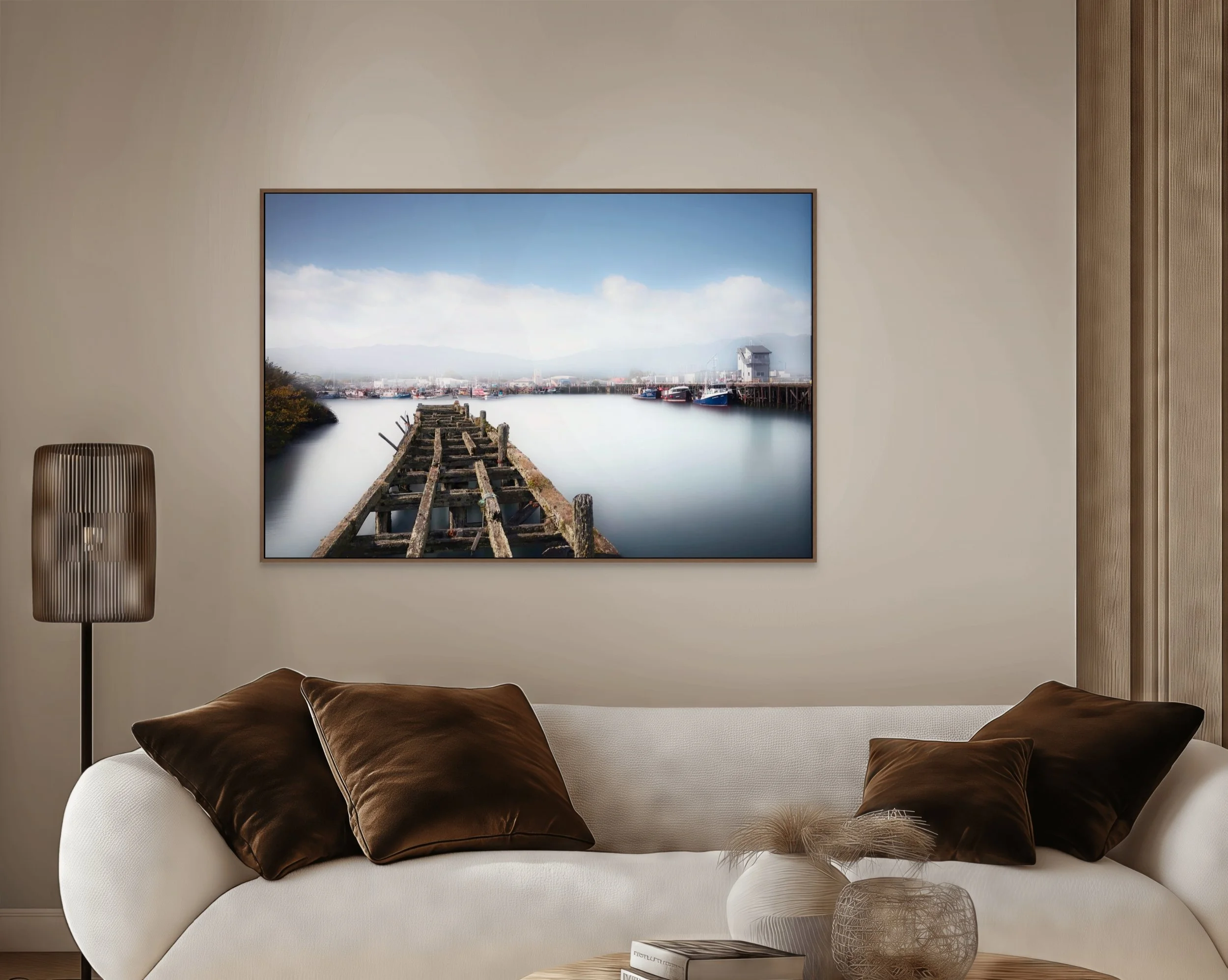 Old wooden jetty leading into calm misty harbour with fishing boats.
