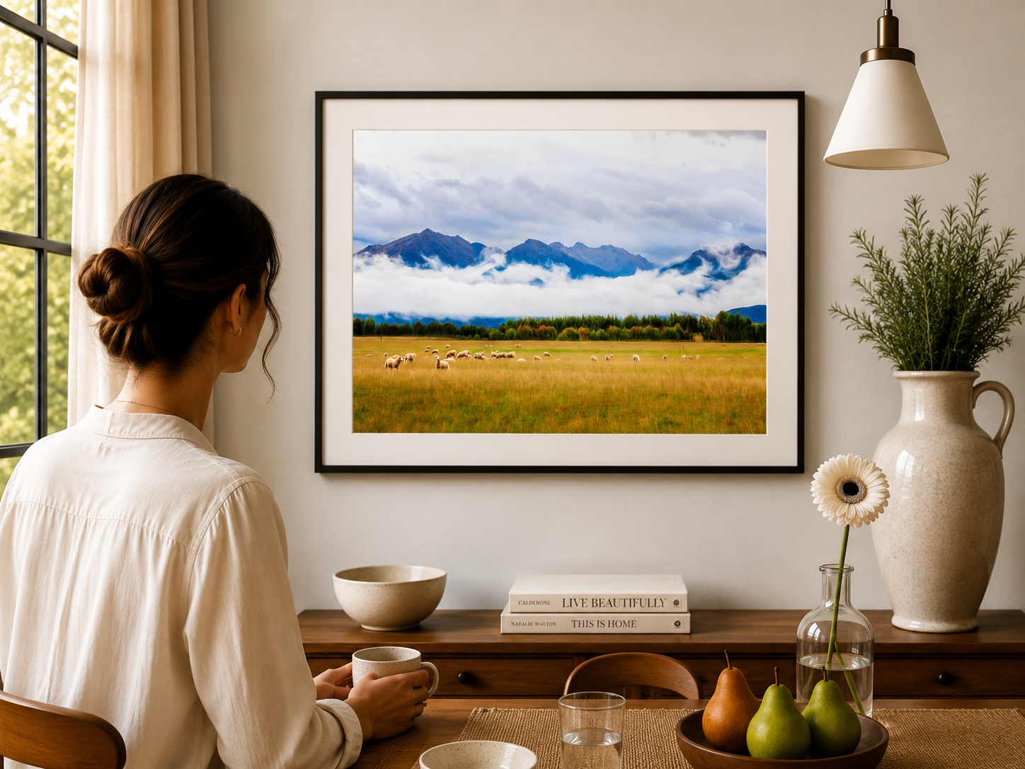 Sheep grazing in a field beneath mountains and low cloud.