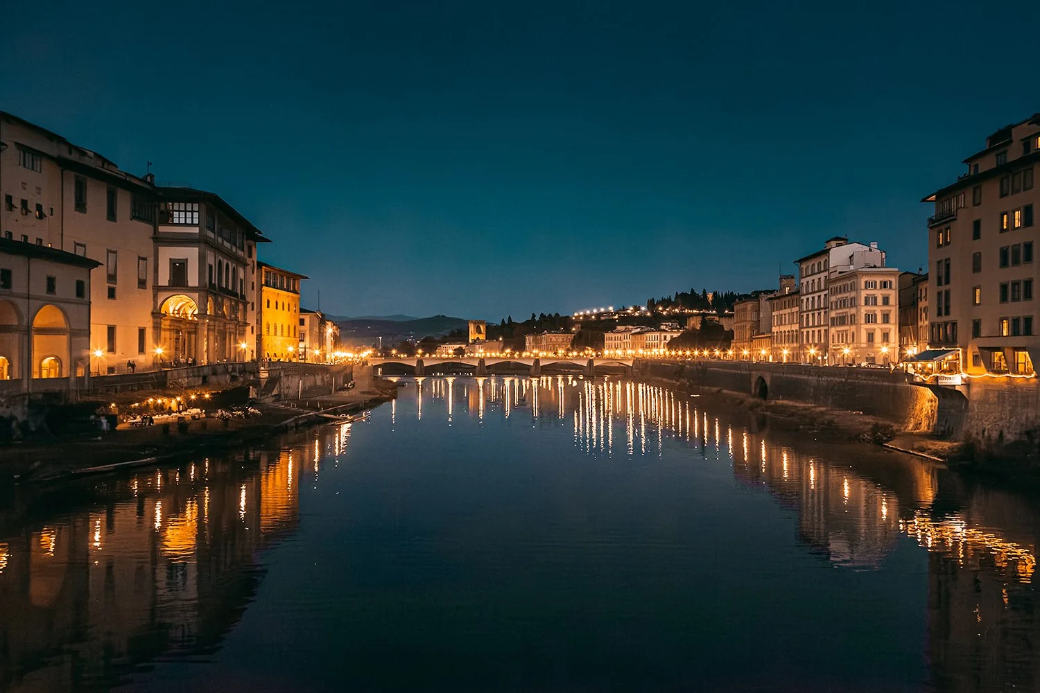 Night view of Florence illuminated along the Arno River.