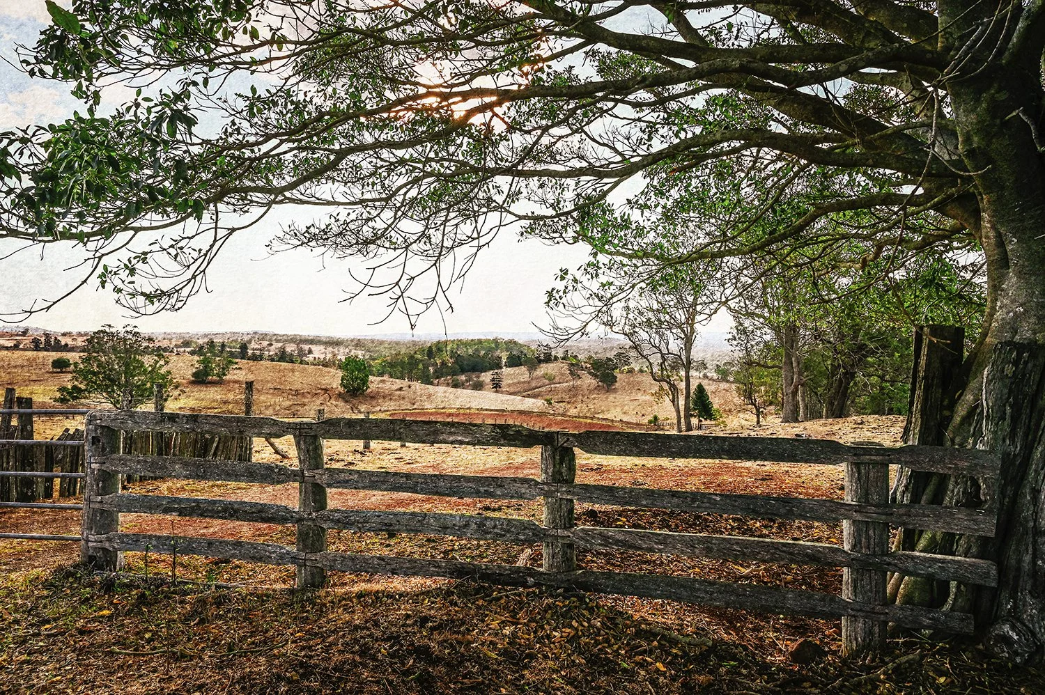 Weathered timber fence overlooking rolling rural hills.