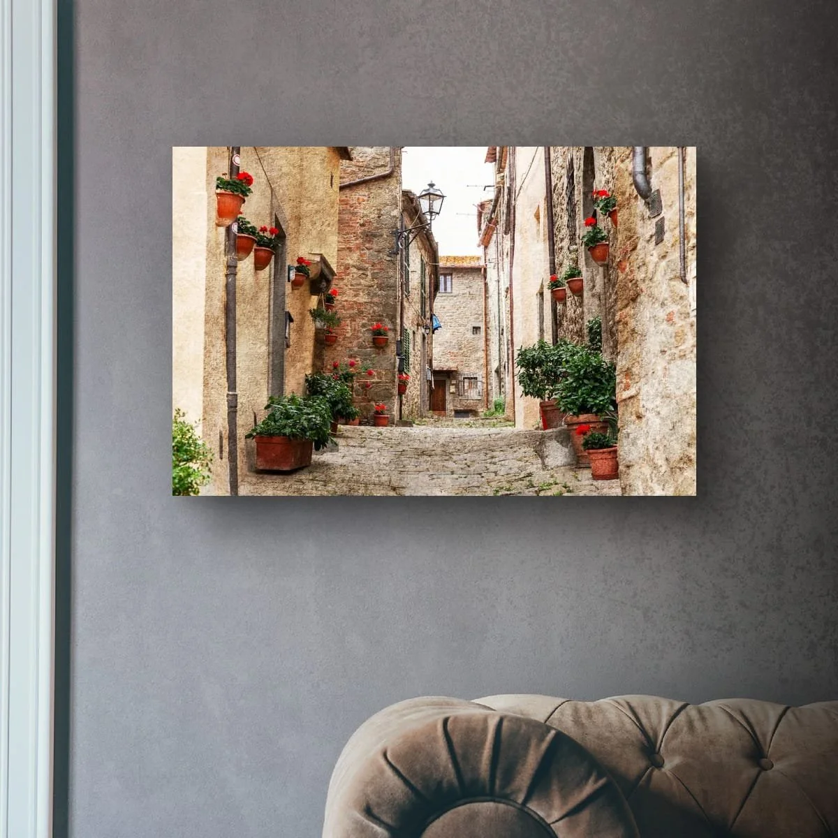 Tuscan laneway lined with red flowers and historic stone buildings.