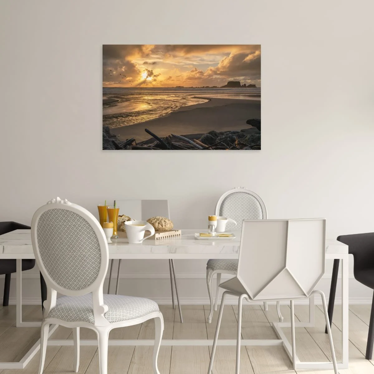 Golden sunlight breaking through clouds over a beach, tidal stream, seabirds and distant rocky sea stacks.
