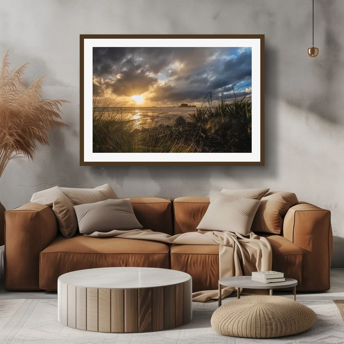 Sun rays breaking through dark coastal clouds over a beach framed by flax, grasses and driftwood.