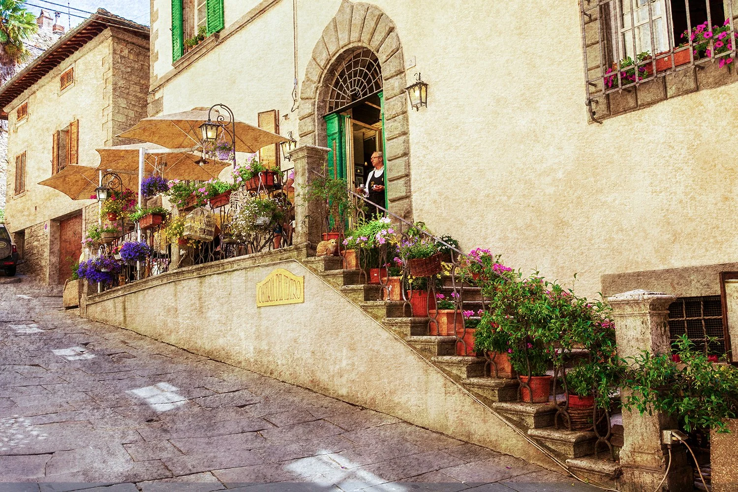 Traditional Italian osteria with flower-lined staircase and stone facade.
