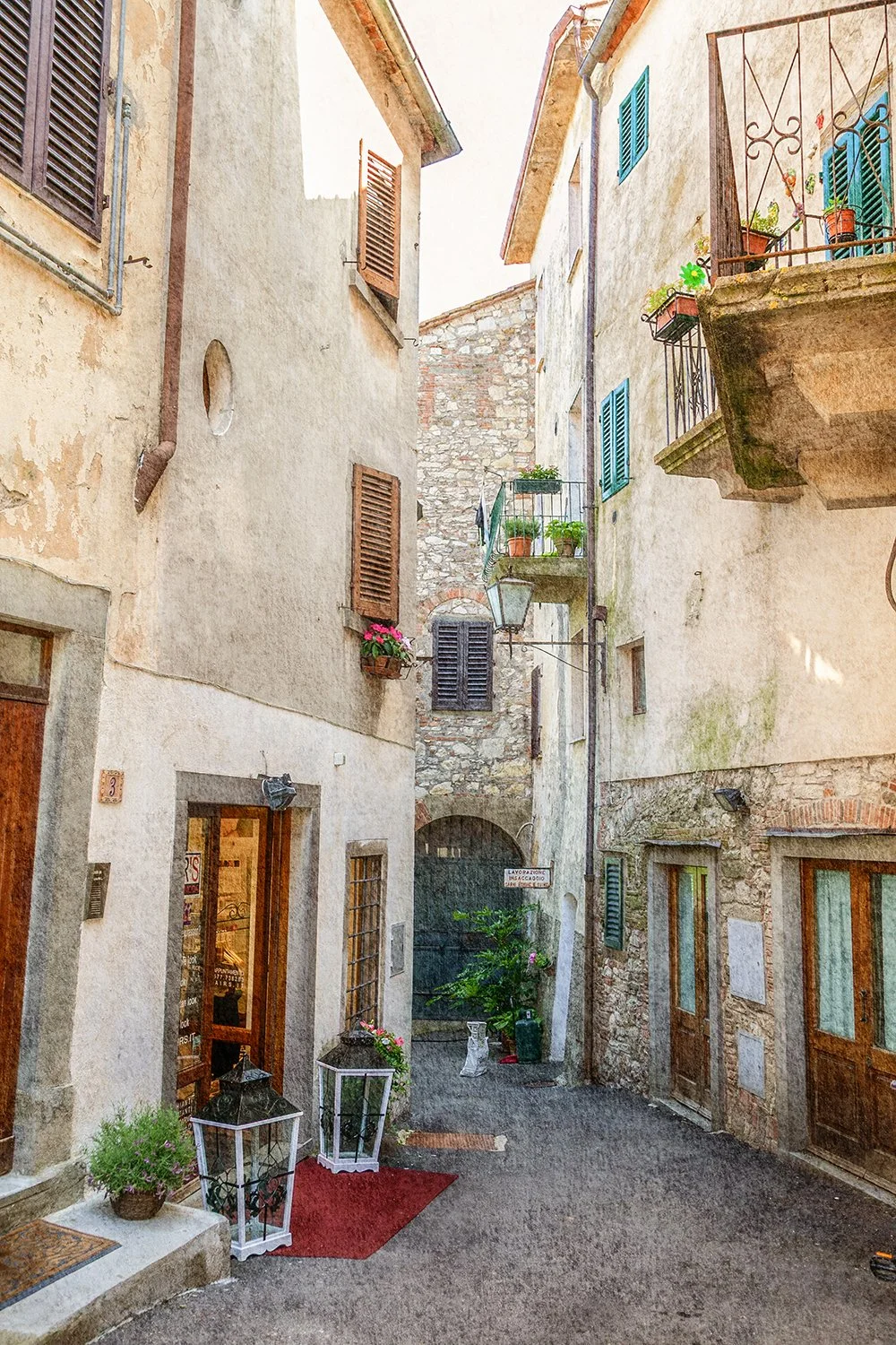 Narrow Italian laneway with stone walls and shutters.