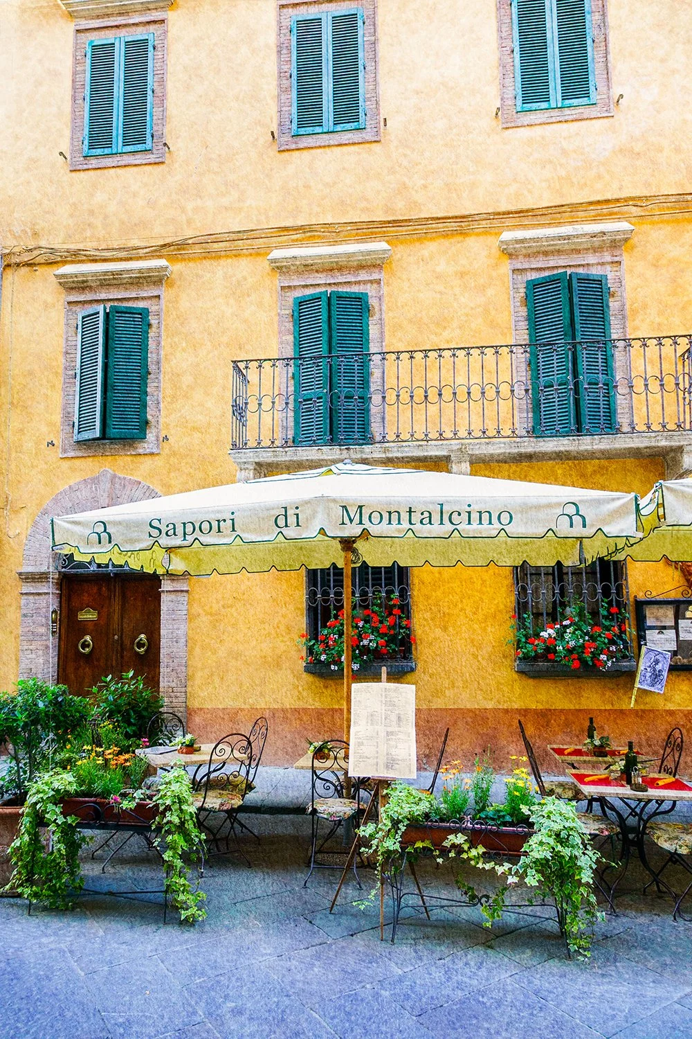 Italian café terrace with umbrellas and flowers.