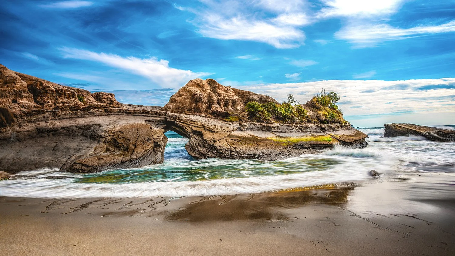 Natural coastal rock arch with ocean waves flowing beneath on the West Coast.