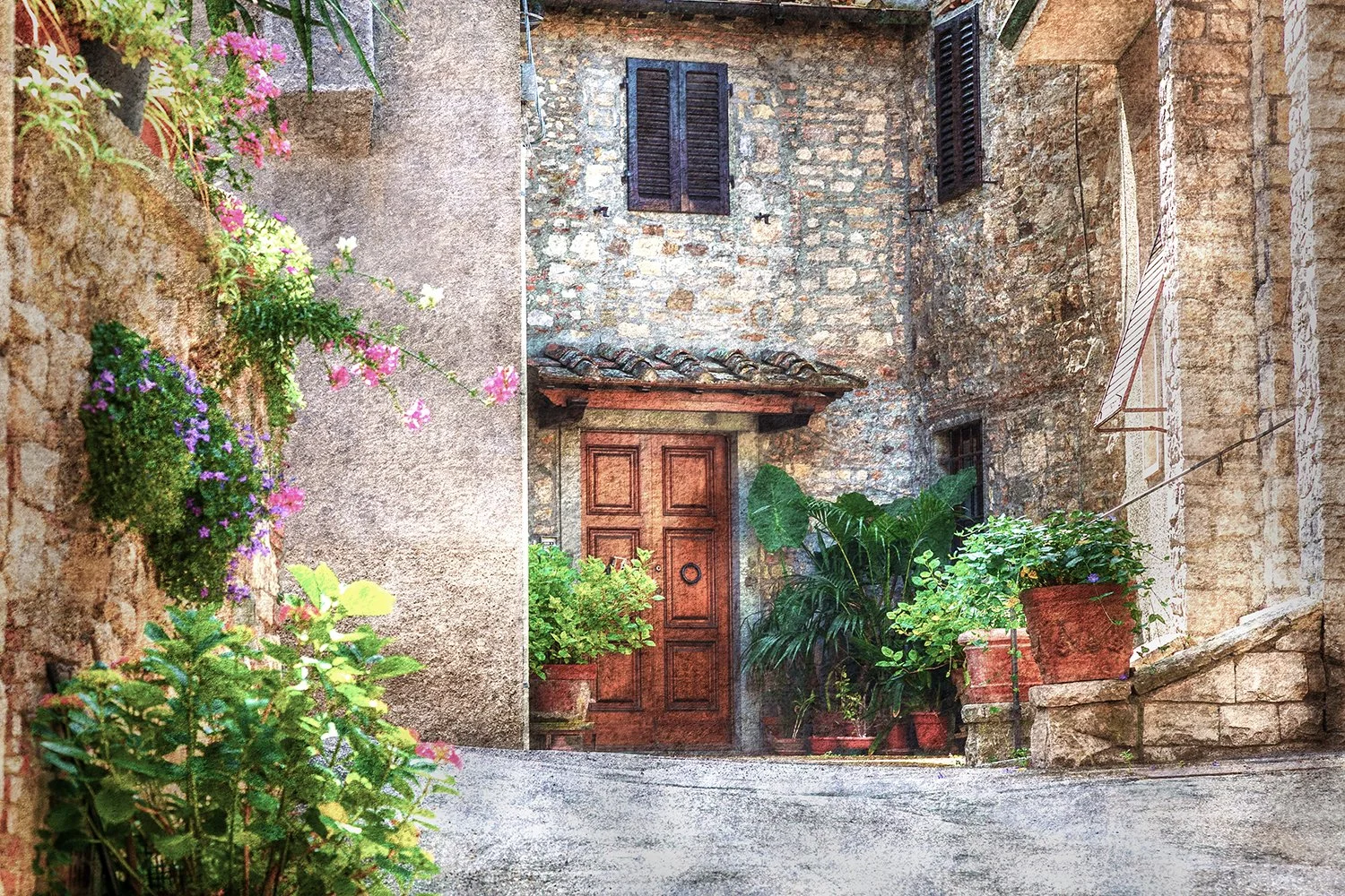 Flowers and stone buildings in an Italian village lane.