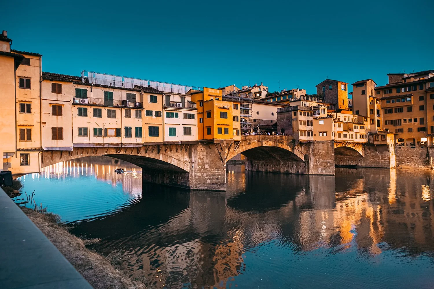 Ponte Vecchio bridge reflected in the Arno River at dusk.