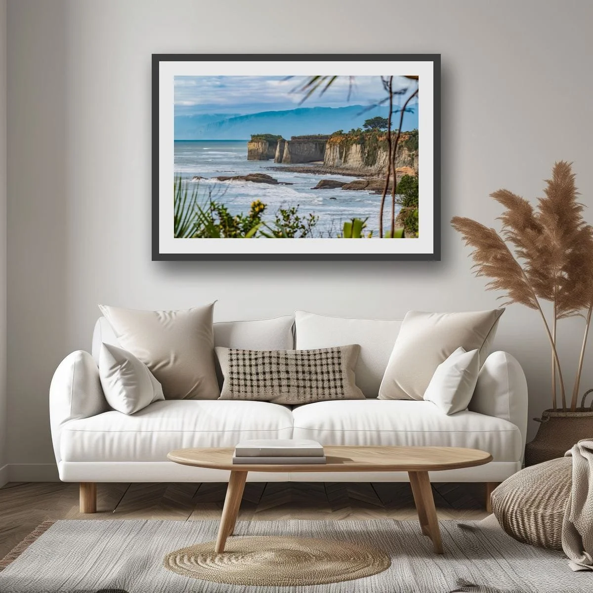 Native coastal plants framing limestone cliffs and the Tasman Sea on New Zealand's West Coast.