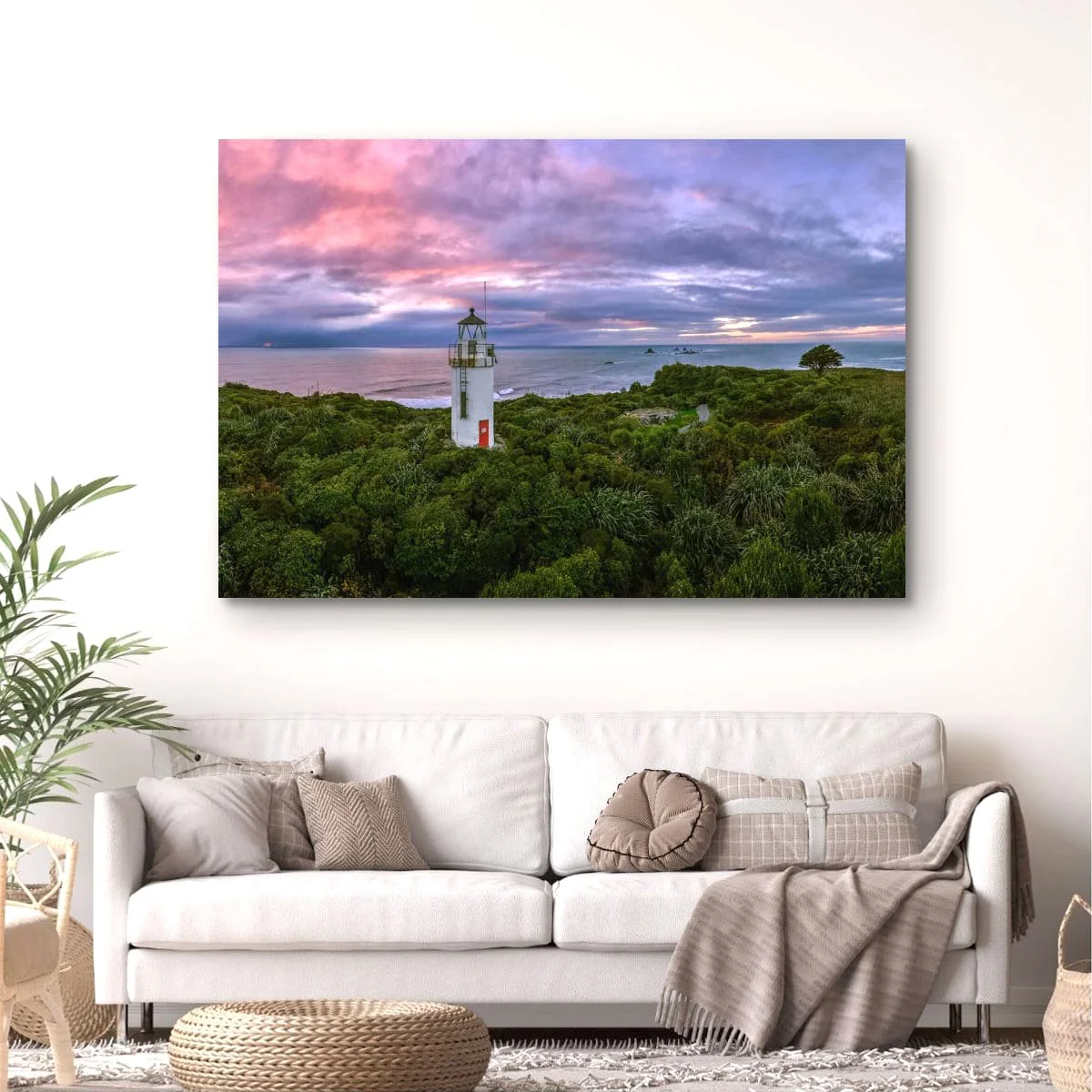 Panoramic view of a historic lighthouse surrounded by native bush at sunset.