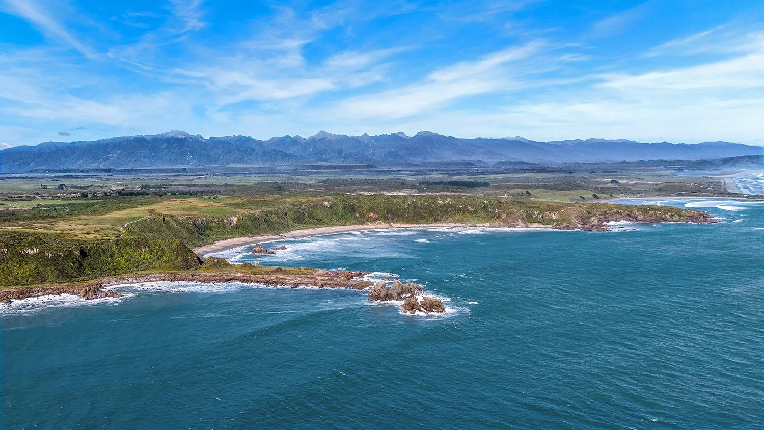 Aerial view of West Coast bays, headlands and mountain ranges.