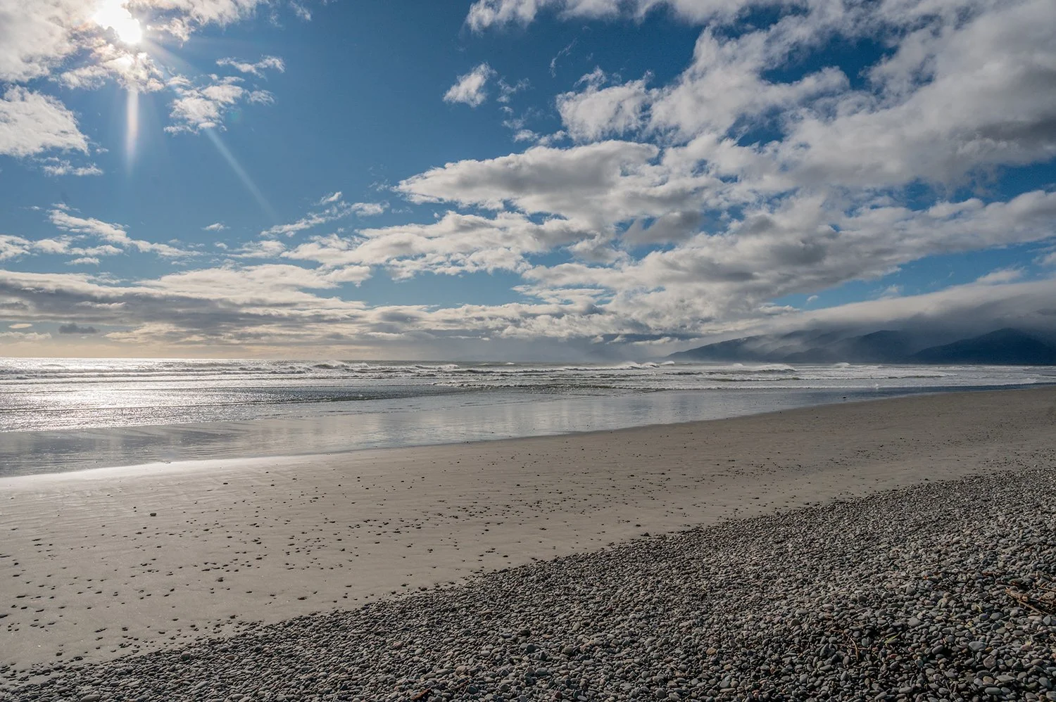 Ocean meeting mountain ranges beneath dramatic clouds.