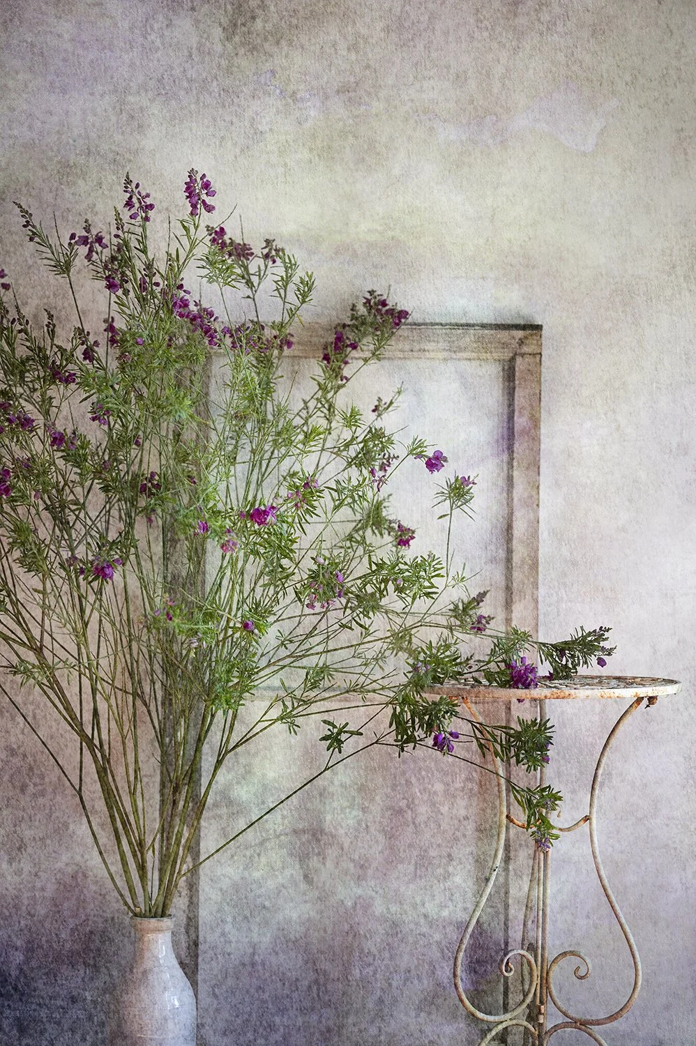 Purple wildflowers arranged beside a vintage table.