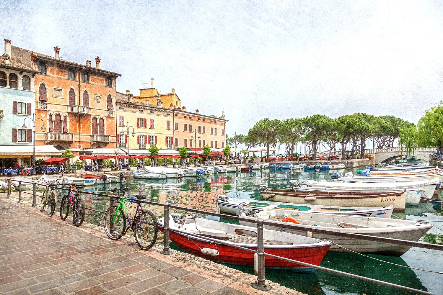 Italian waterfront village with boats, cafés and historic buildings.