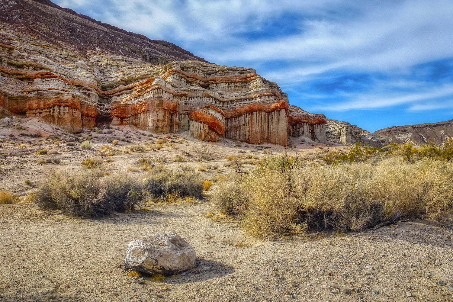 Layered desert rock formations in the Mojave Desert landscape.