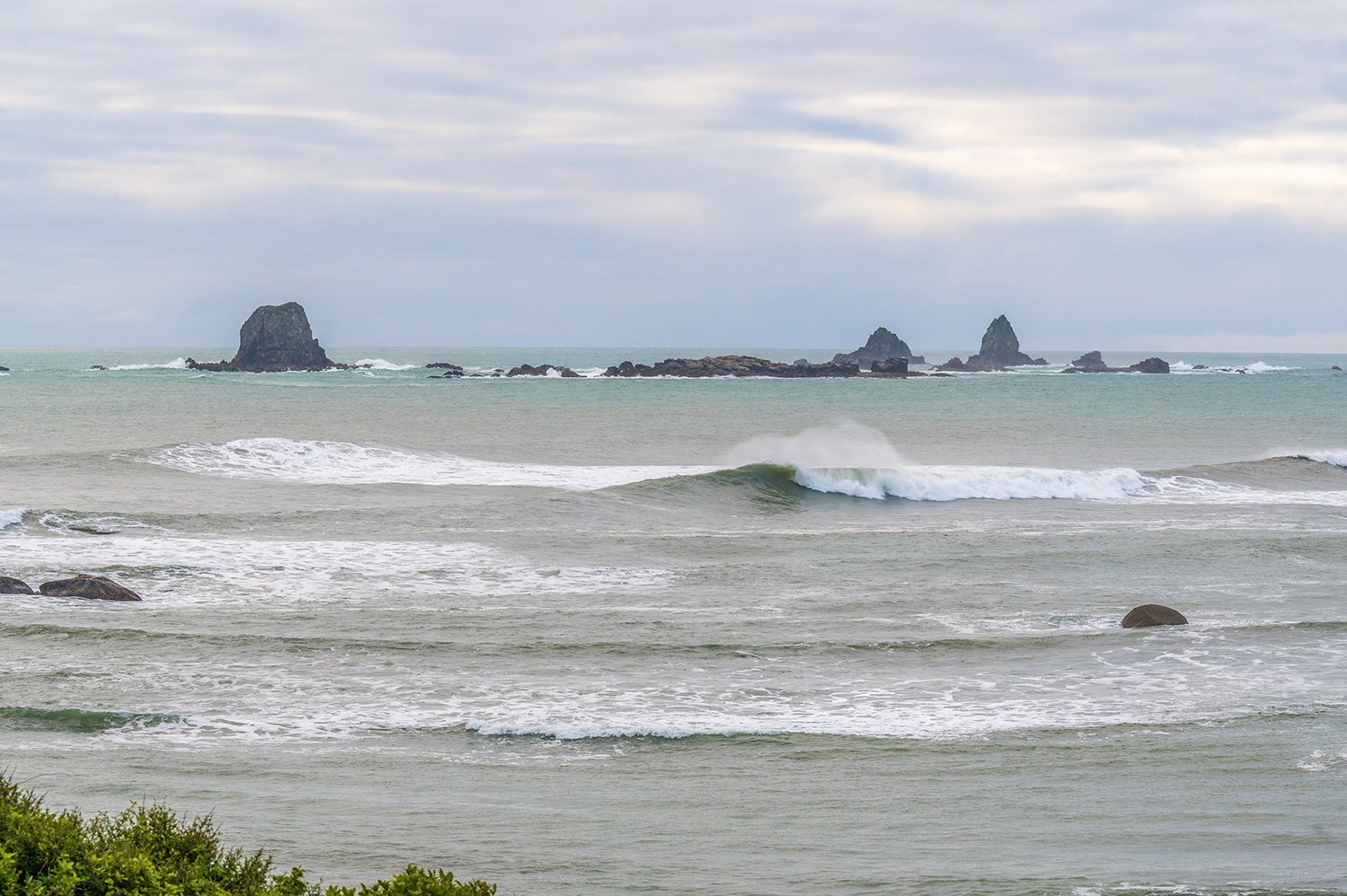 Building ocean swell beneath cloud-covered mountain ranges.