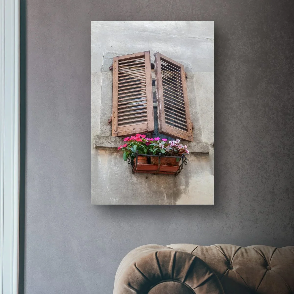 Rustic Italian window with wooden shutters and pink flowers in a window box.