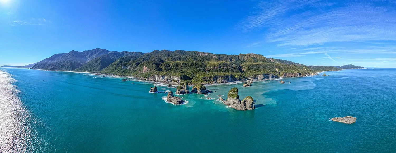 Aerial panorama of West Coast sea stacks, coastline and native forest.