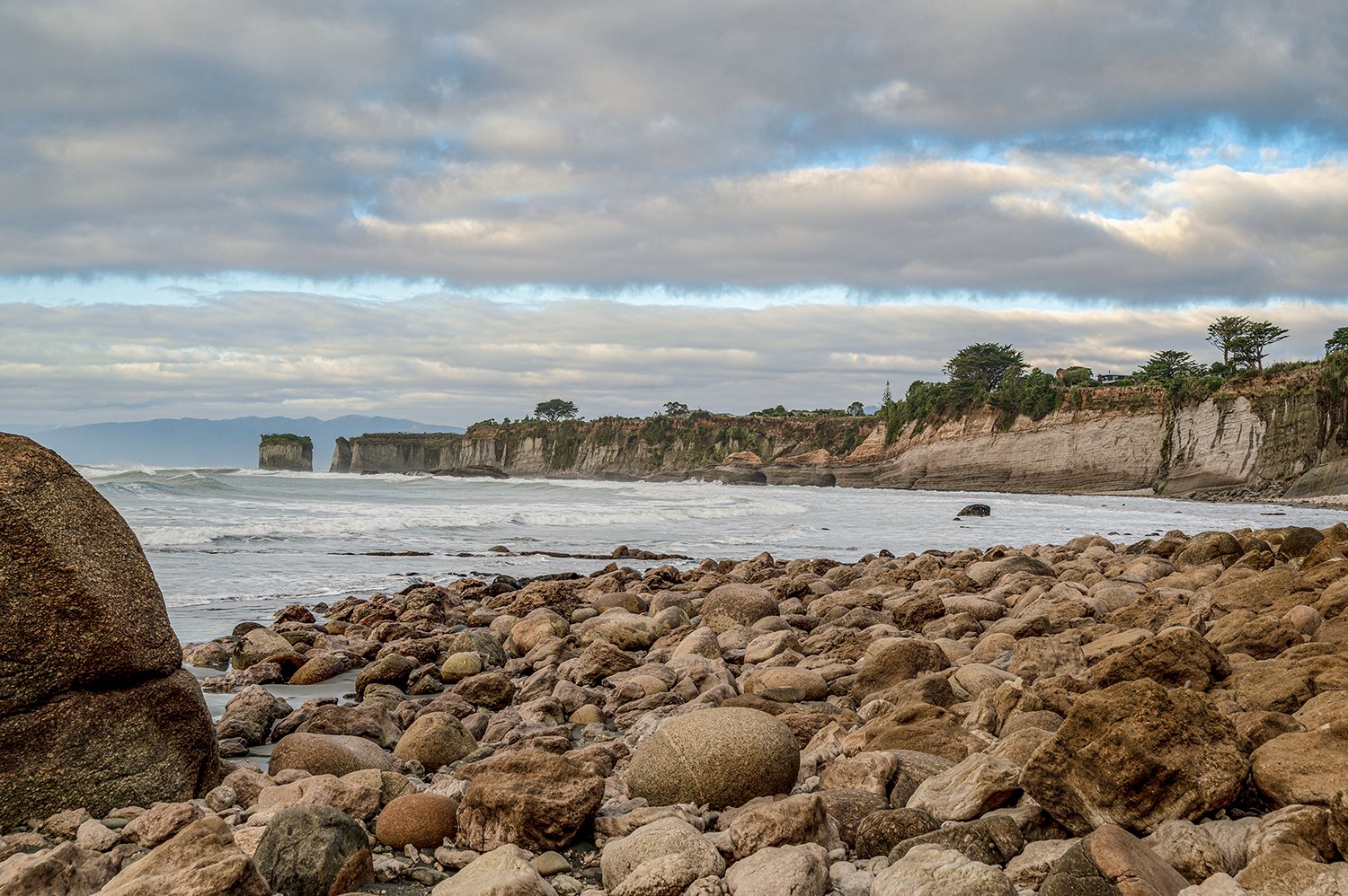 Rocky shoreline leading to limestone cliffs on New Zealand's West Coast.